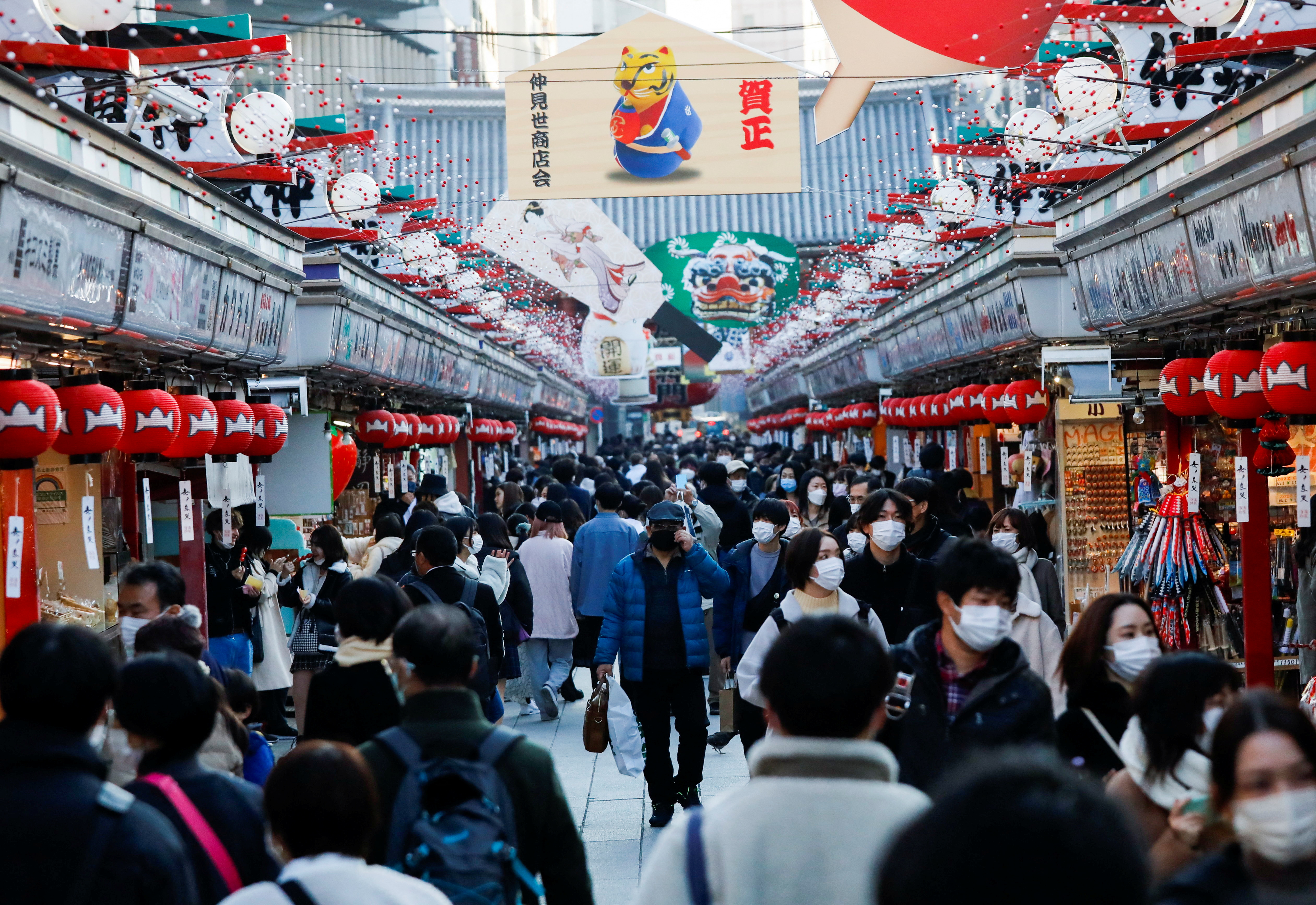Visitors wearing protective face masks walk under decorations for the New Year at Nakamise street leading to Senso-ji temple at Asakusa district amid the COVID-19 pandemic, in Tokyo