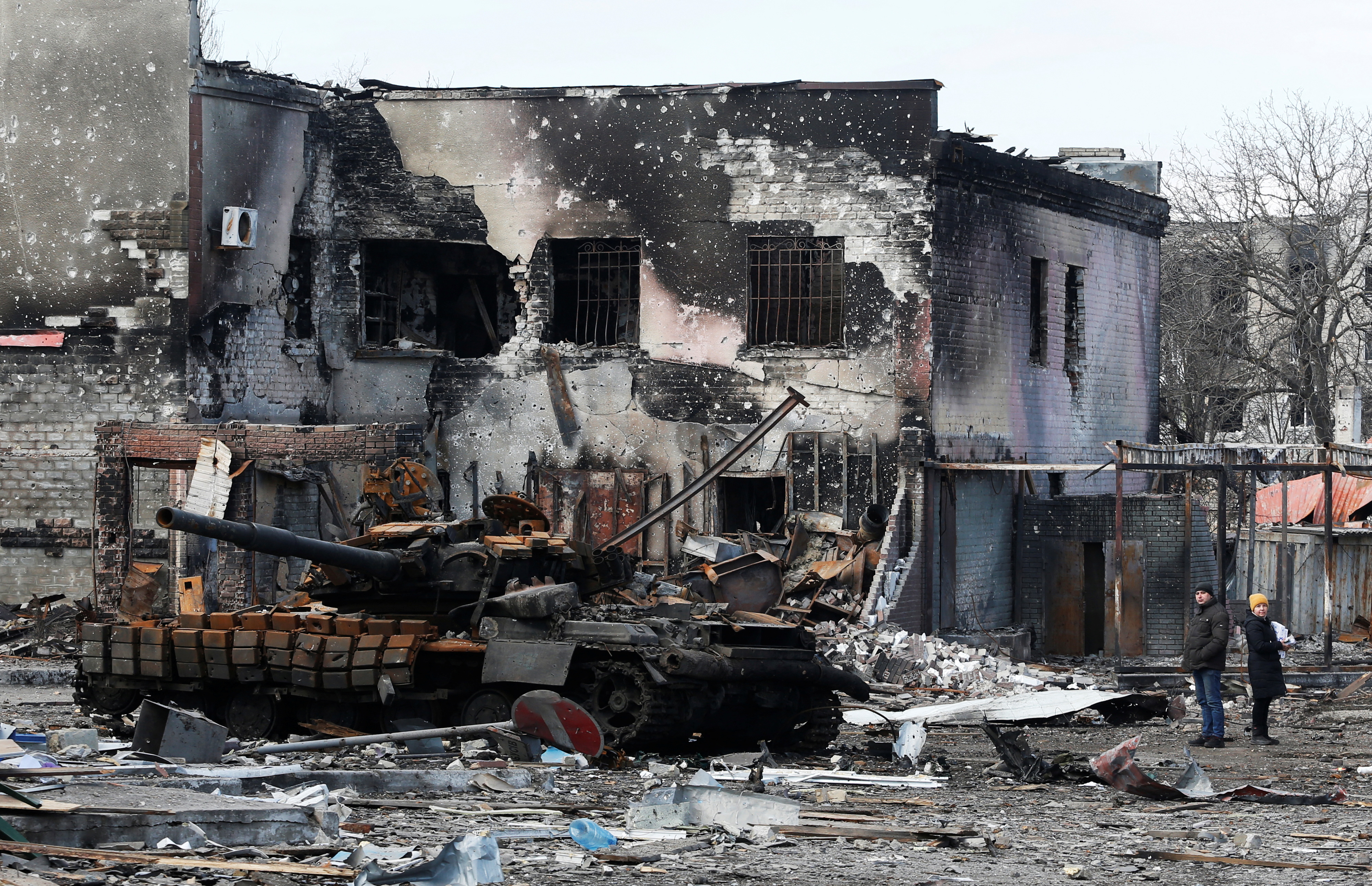 Local residents are seen next to a destroyed armoured vehicle during Ukraine-Russia conflict in the separatist-controlled town of Volnovakha in the Donetsk region, Ukraine March 15, 2022.