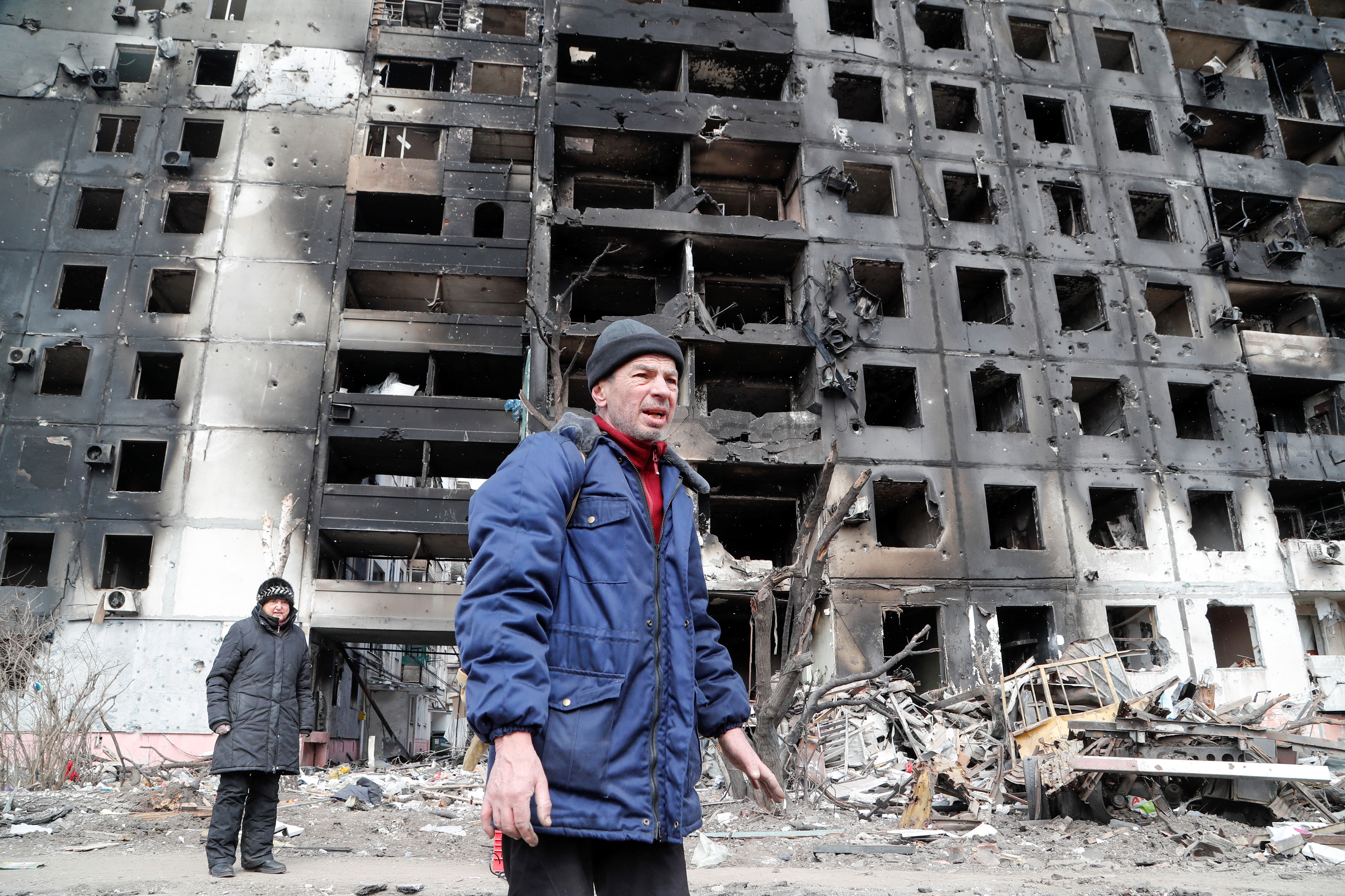 People gather near a block of flats, which was destroyed during Ukraine-Russia conflict in the besieged southern port city of Mariupol,