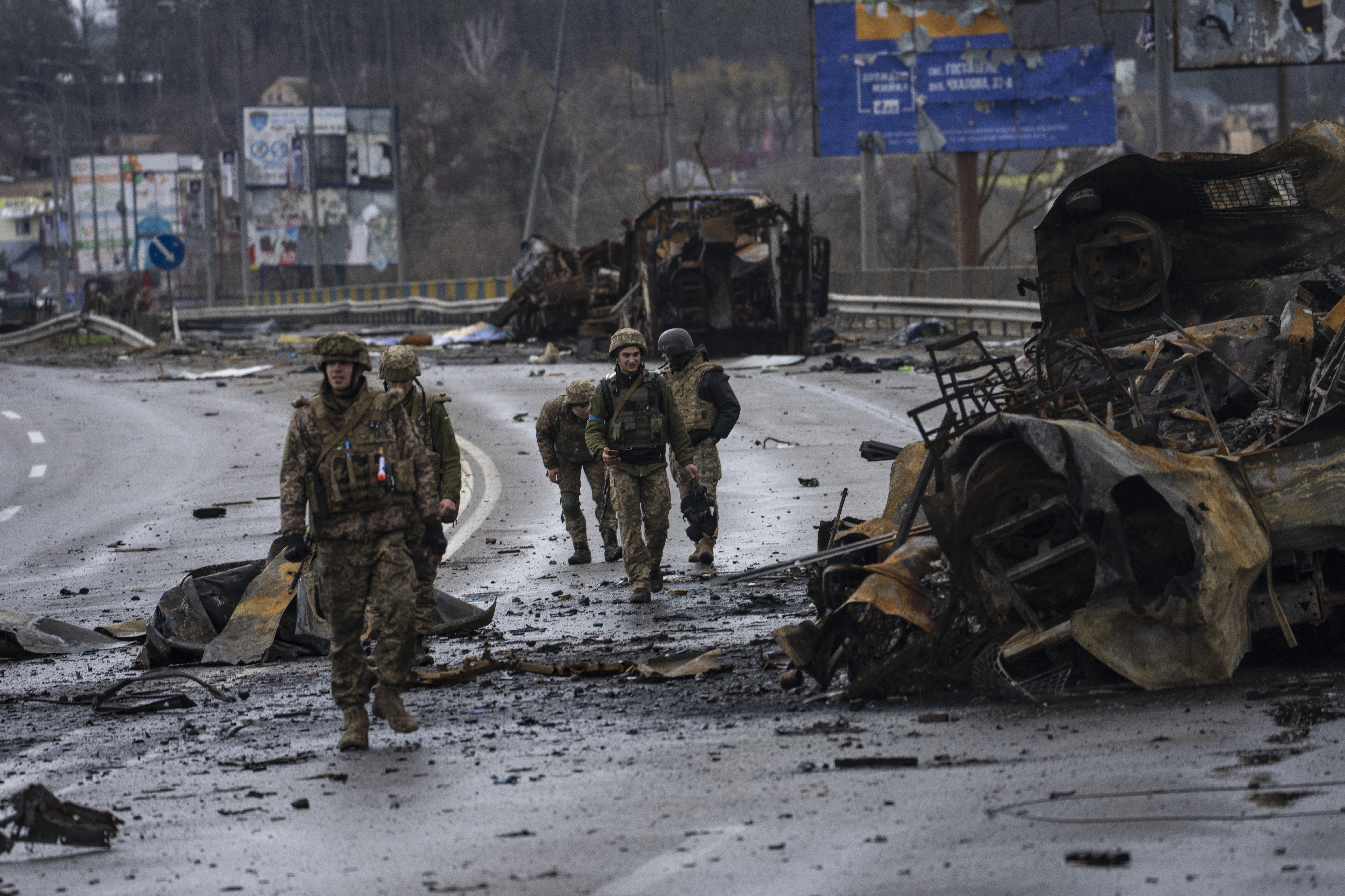 Ukrainian soldiers walk next to destroyed Russians armored vehicles