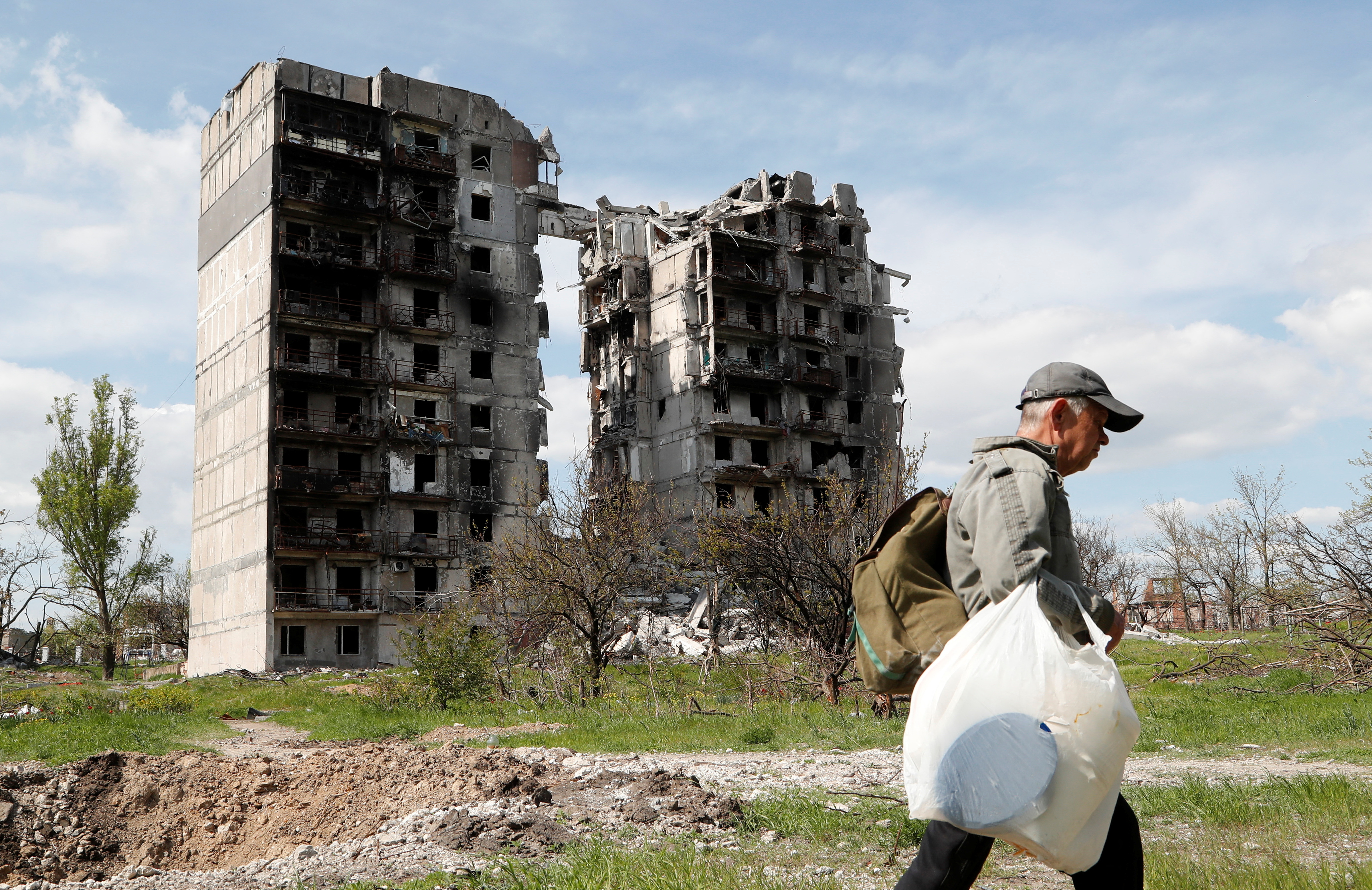 A man walks near a destroyed residential building in Mariupol