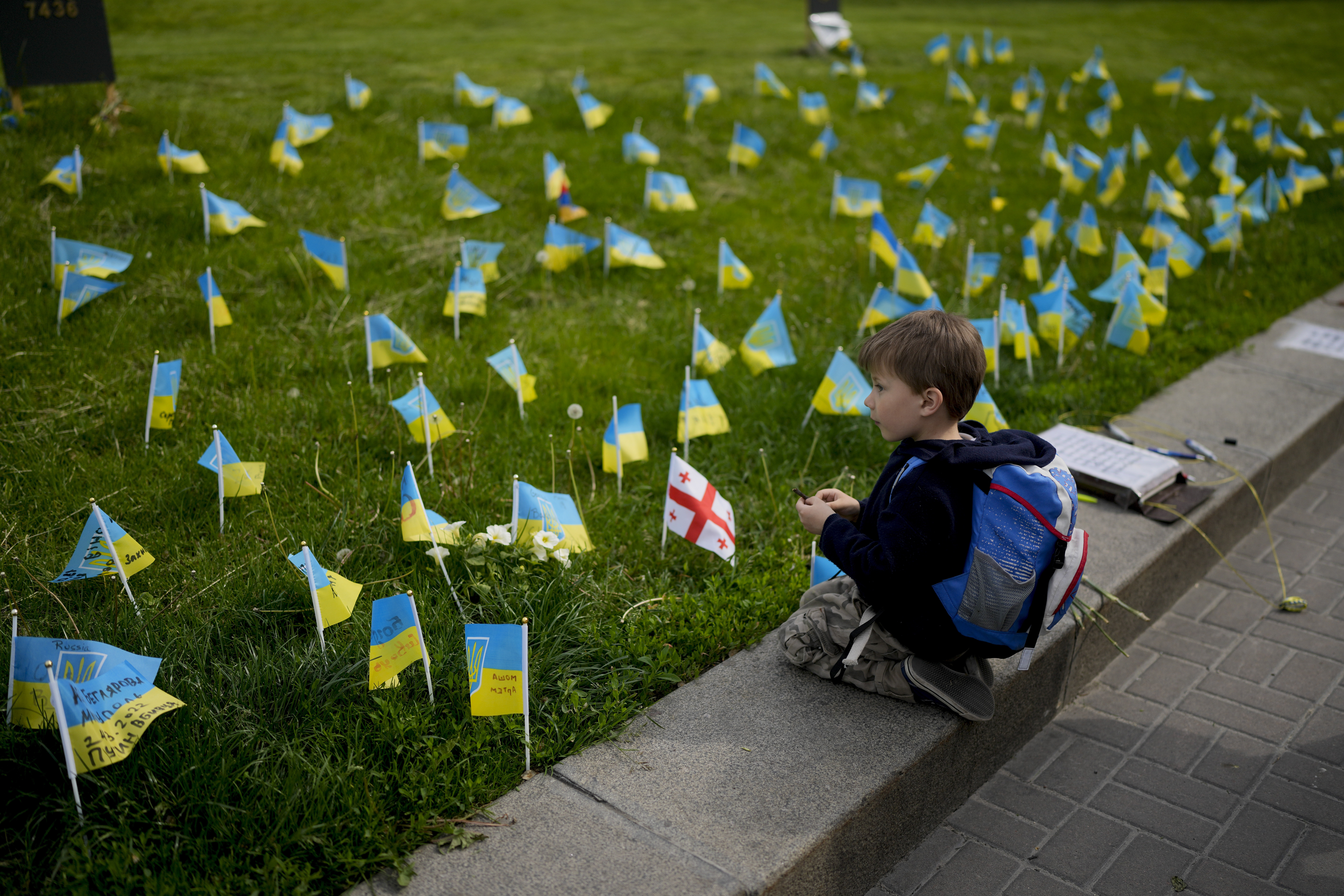 A boy watches flags honoring soldiers killed fighting Russian troops in downtown Kyiv, Ukraine, Monday, May 23, 2022.