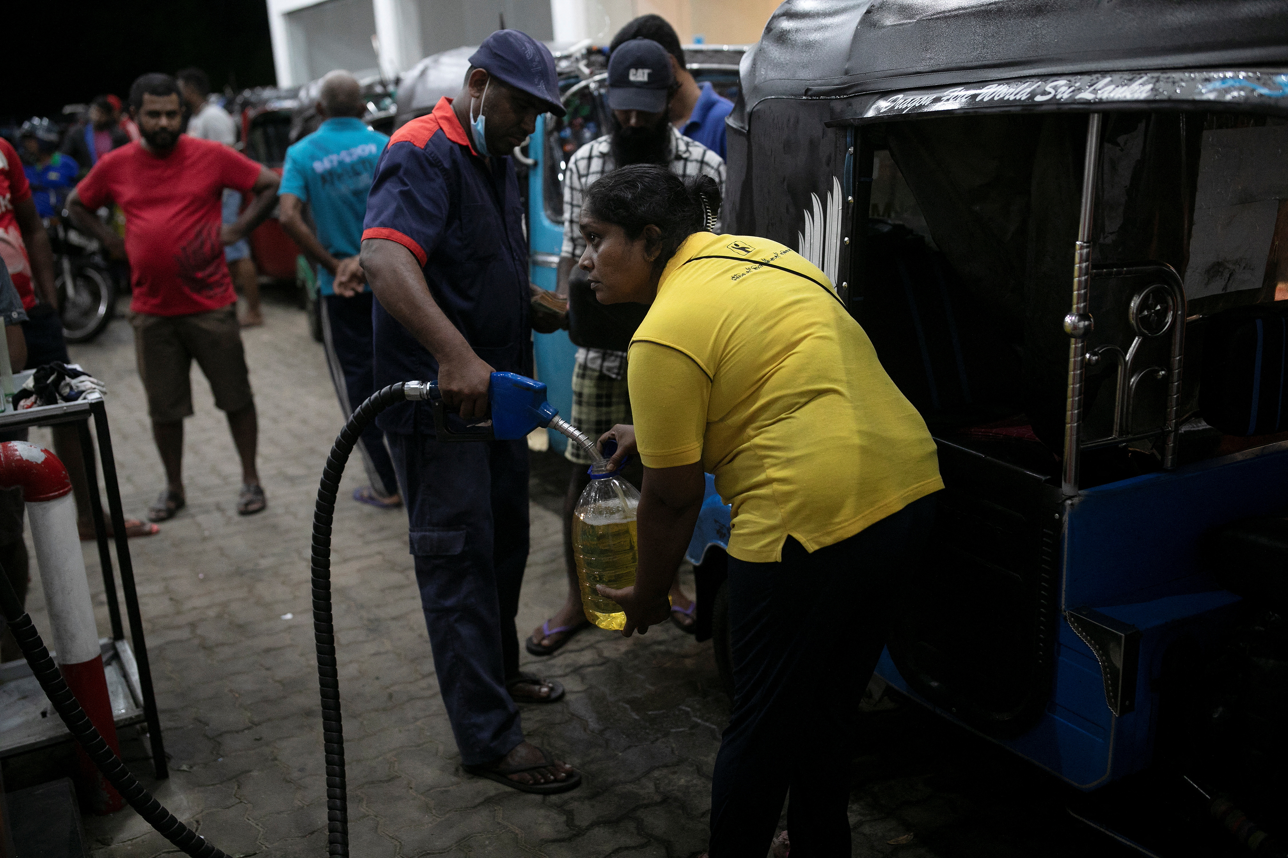 Lasanda Deepthi, 43, an auto-rickshaw driver for local ride hailing app PickMe, has a container filled with petrol during the early hours of the morning at a fuel station in Gonapola town, on the outskirts of Colombo