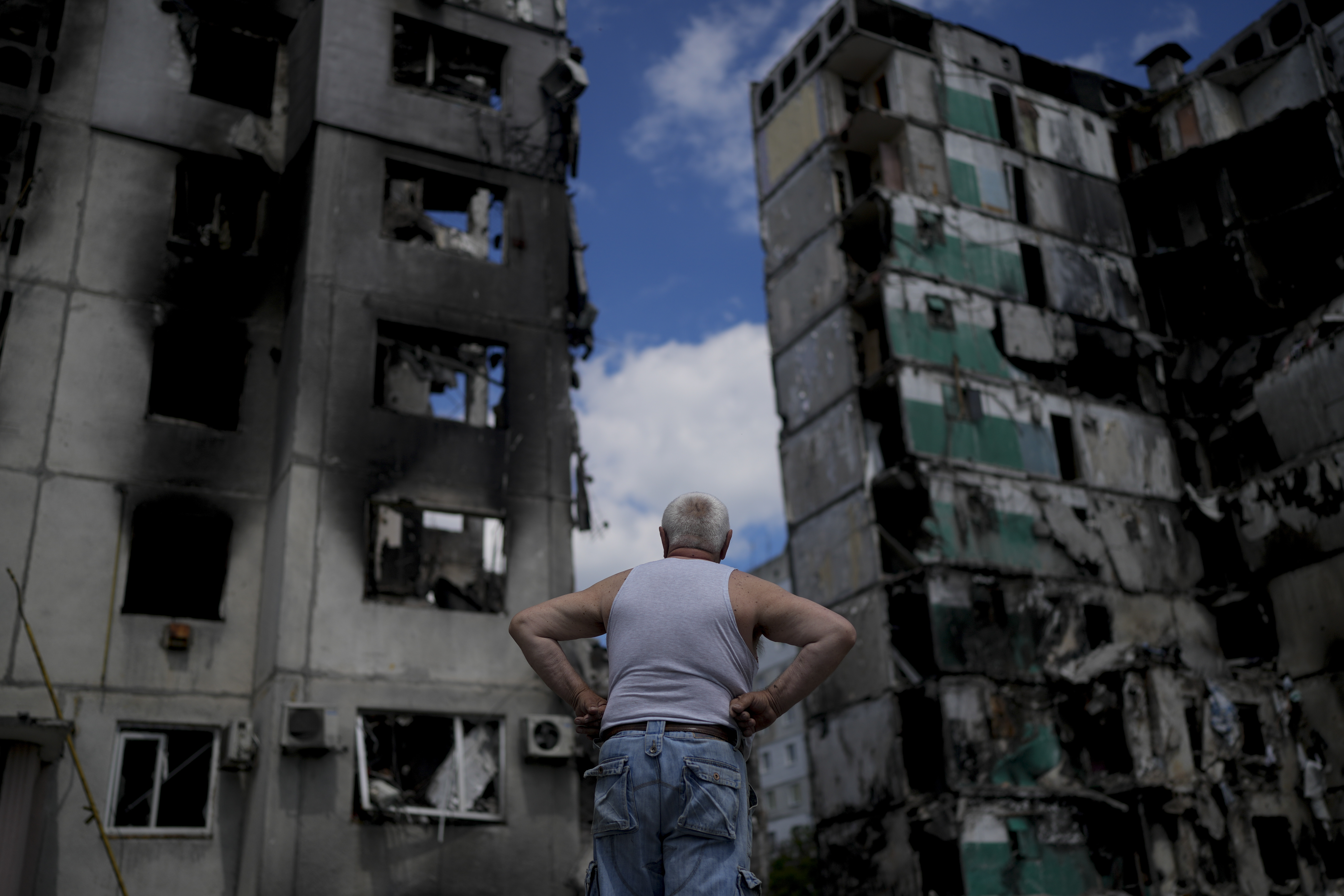 A man is seen looking at a destroyed building on the outskirts of Kyiv