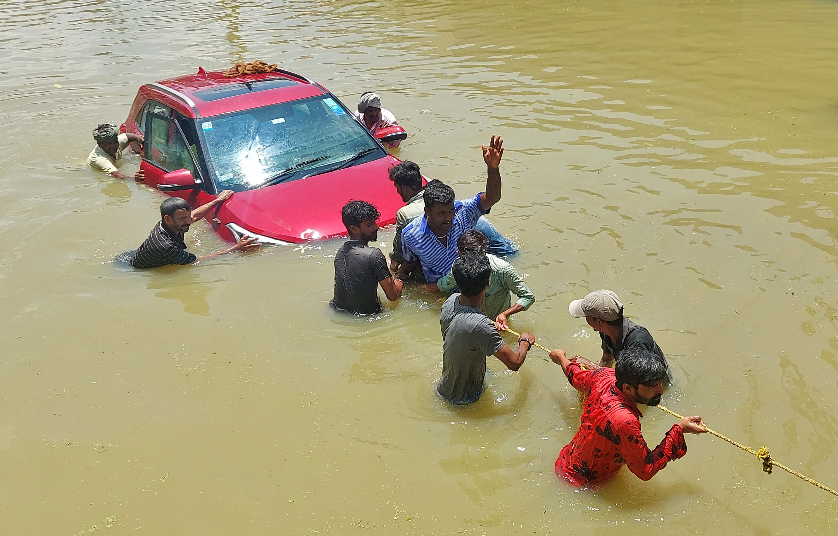 People pull a car through a water-logged road in Bengaluru [Reuters]