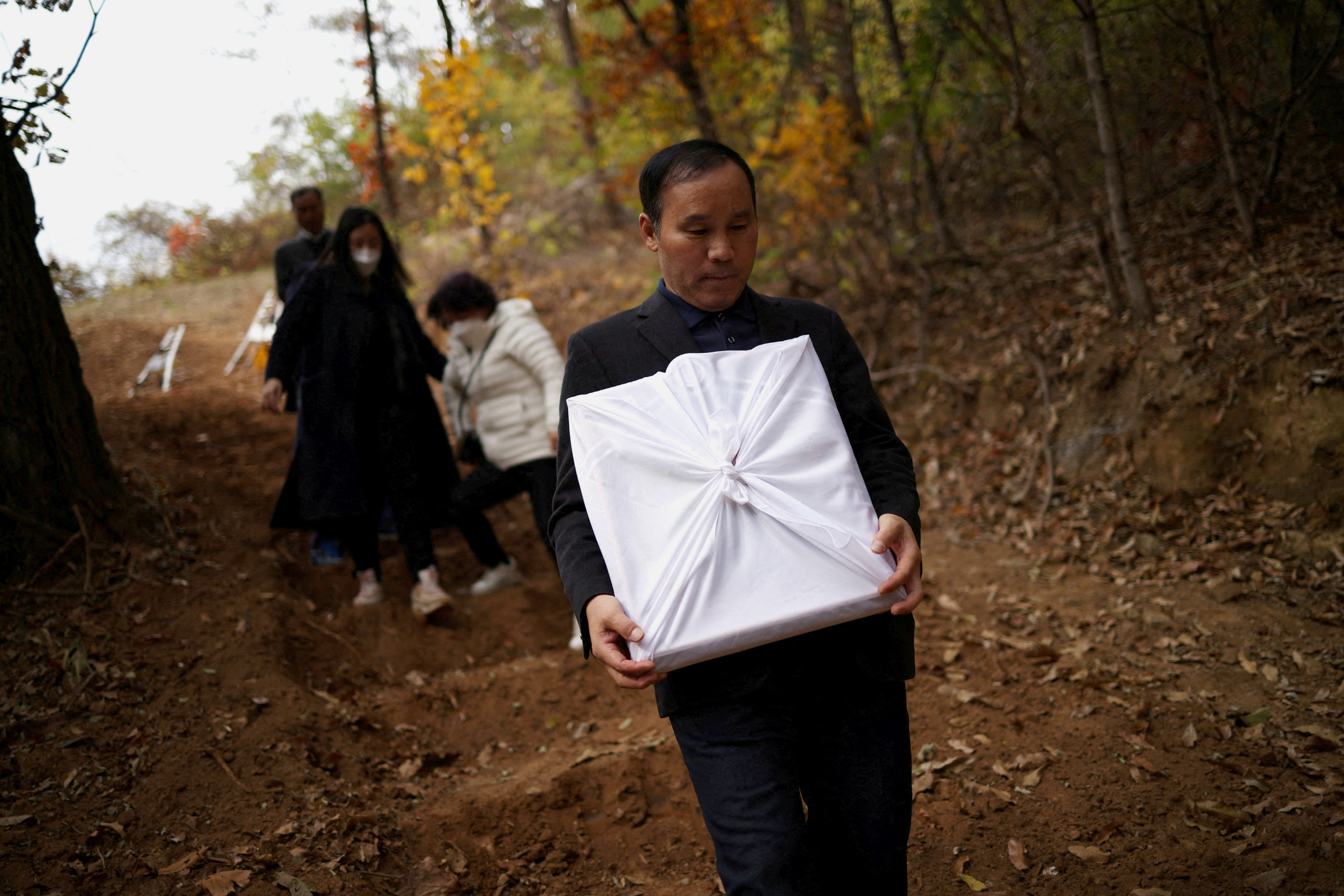 Jung Hae-moon, leaves his daughter's grave holding her portrait.