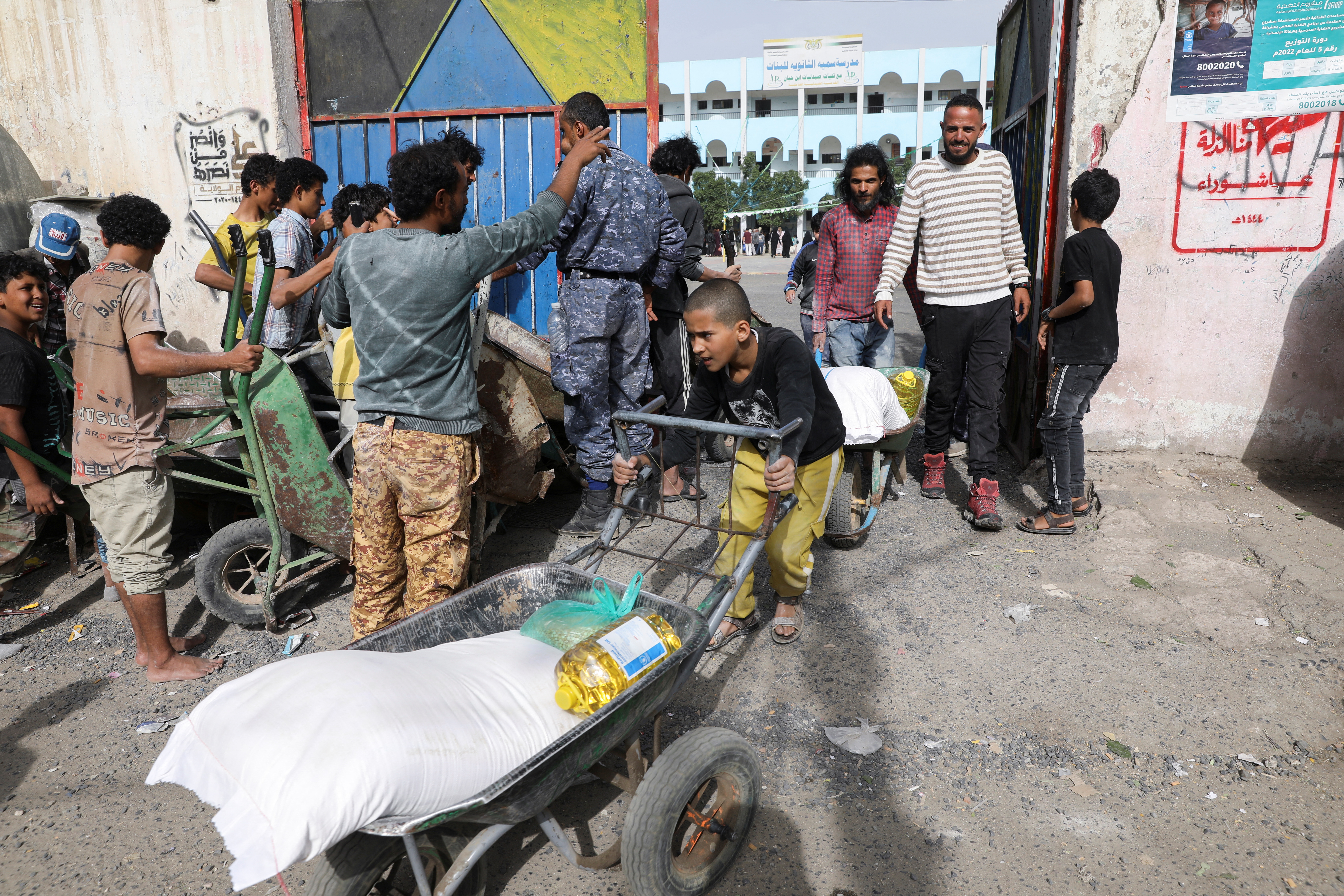 A boy pushes a wheel cart with wheat flour in Sanaa