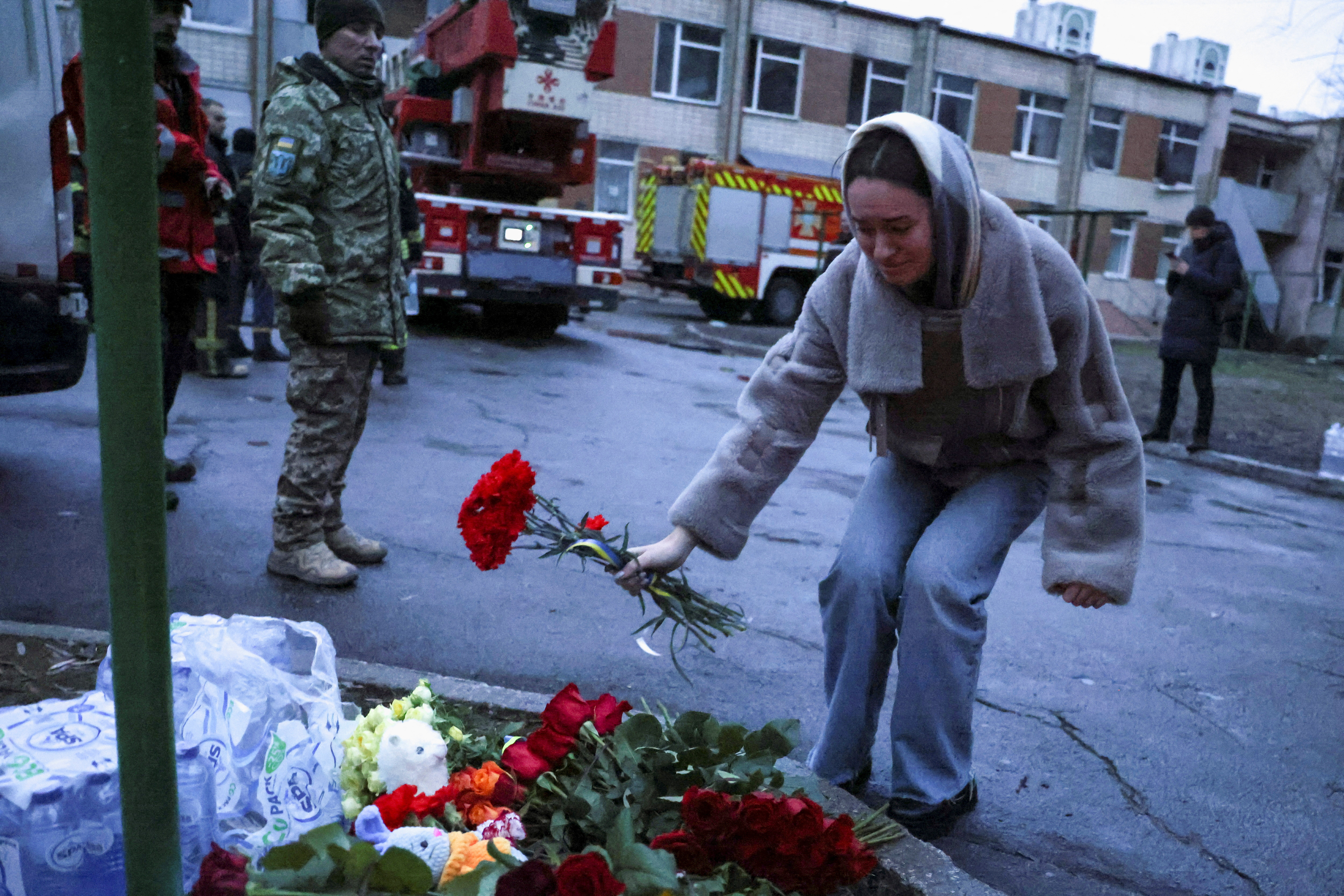 A woman lays flowers near the site of the helicopter crash in Brovary, Ukraine