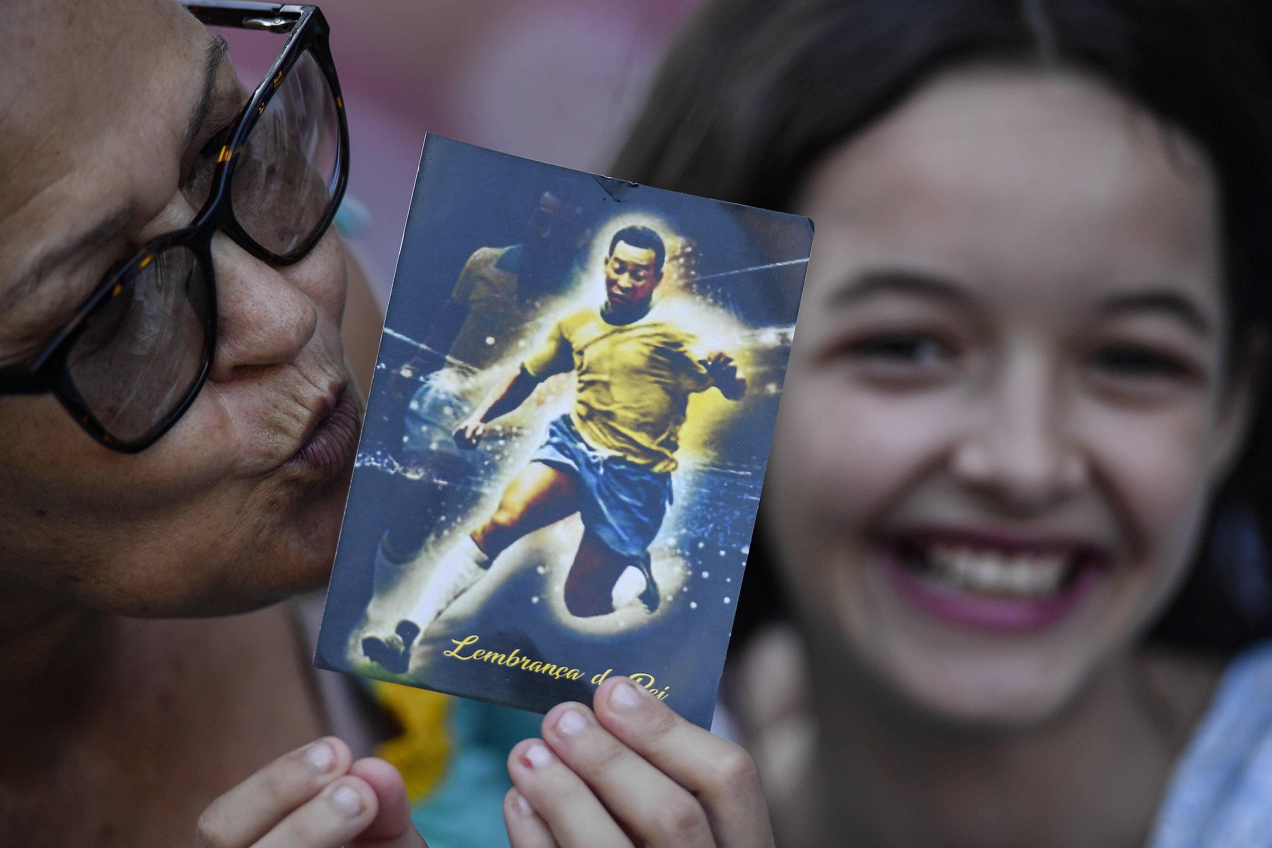A woman kisses a postcard of Pele as she waits in line to enter Vila Belmiro stadium on January 2, 2023