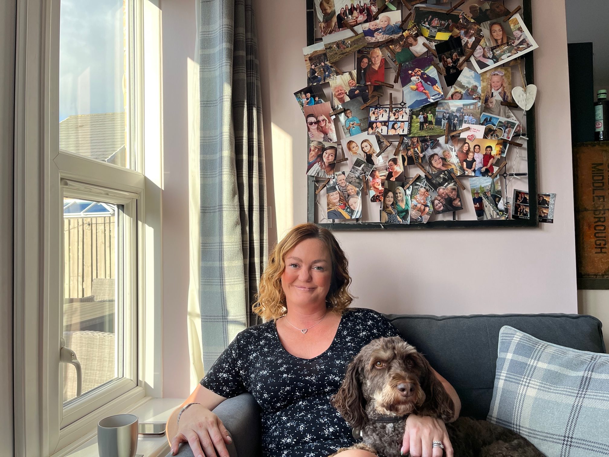 Helen Bone and her dog, Alfie, sit beside a collage of family photos