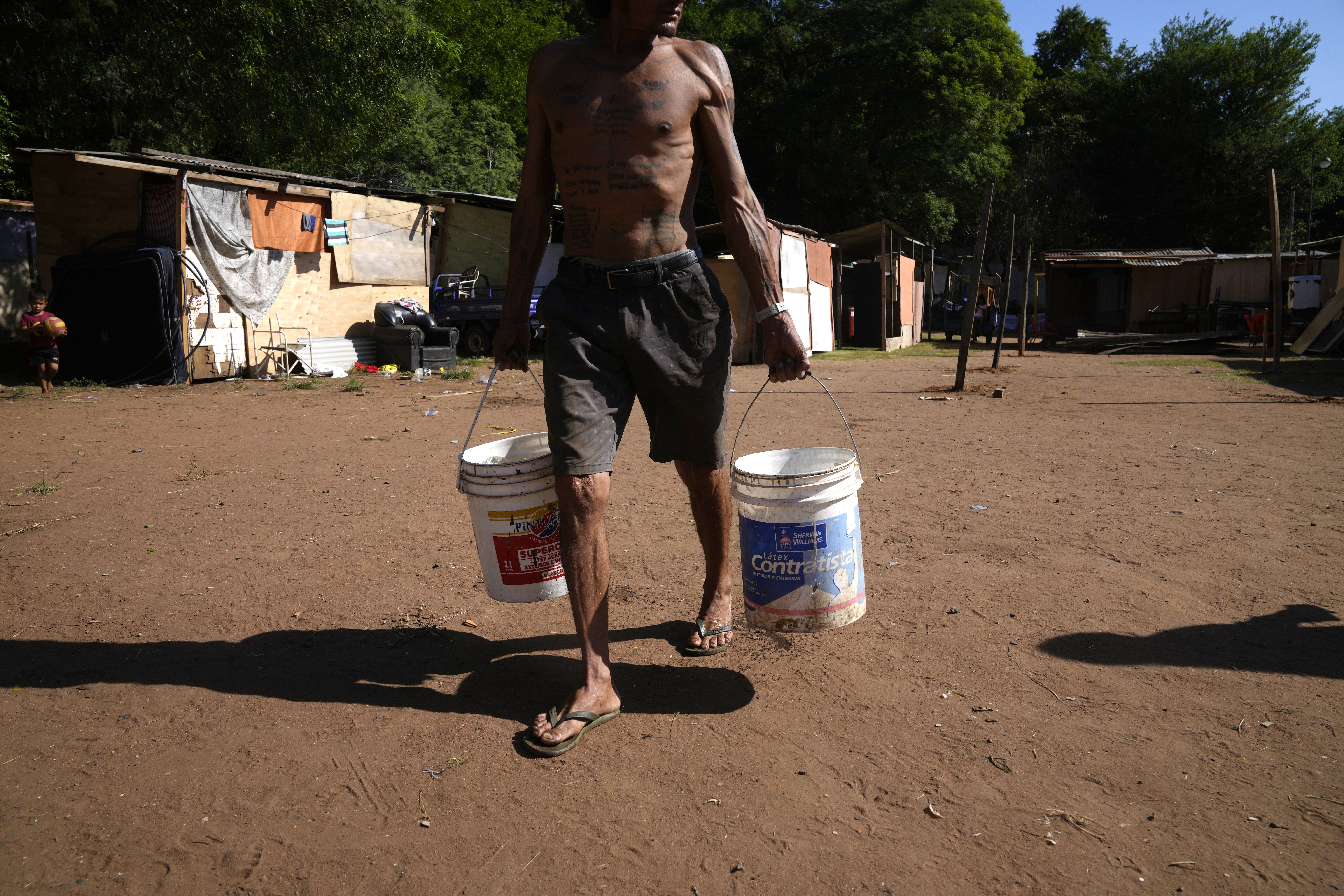 Carmelo Del Valle, who was displaced from his home by the rising waters of the Paraguay River, hauls buckets of water to his temporary shelter, in Asuncion, Paraguay