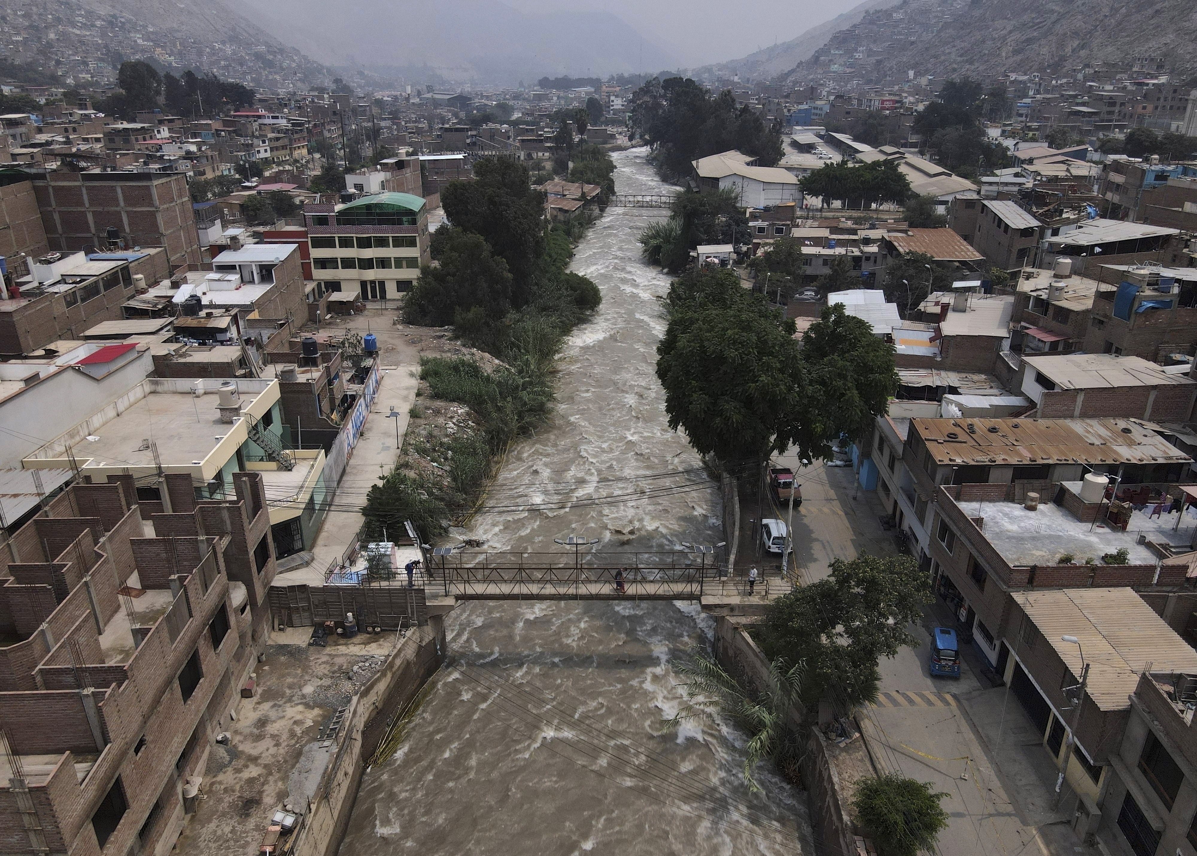 A woman walks on a bridge over the Rimac River, in Lima, Peru