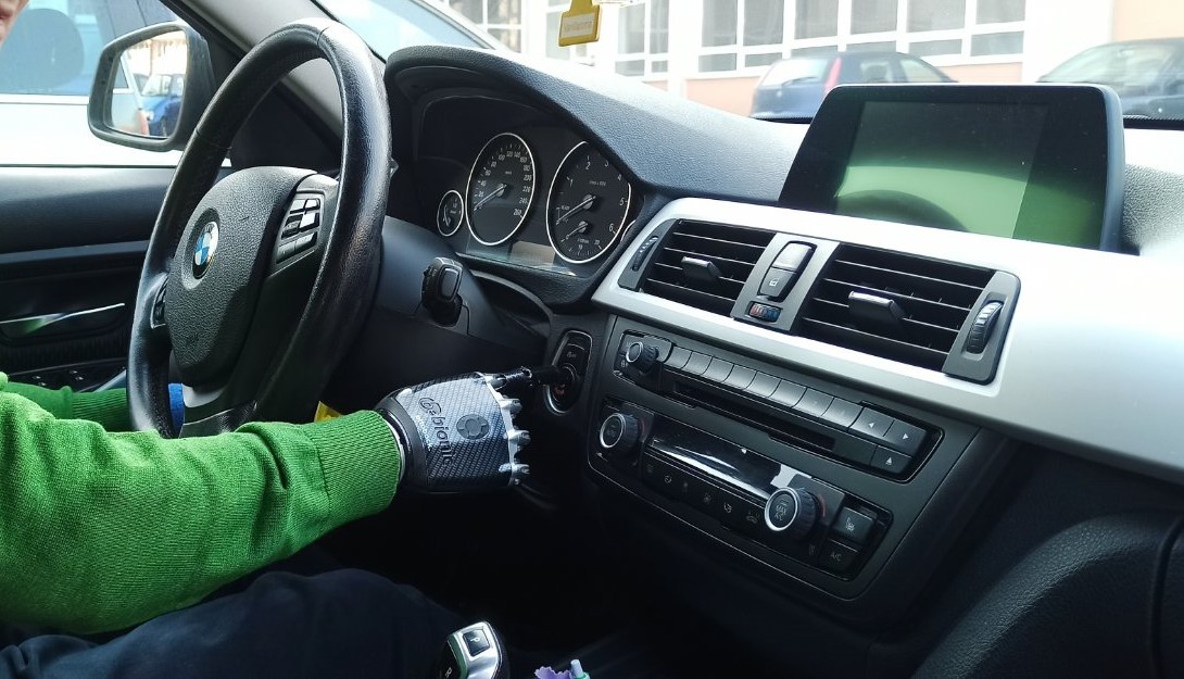 A man with a prosthetic arm starts a car