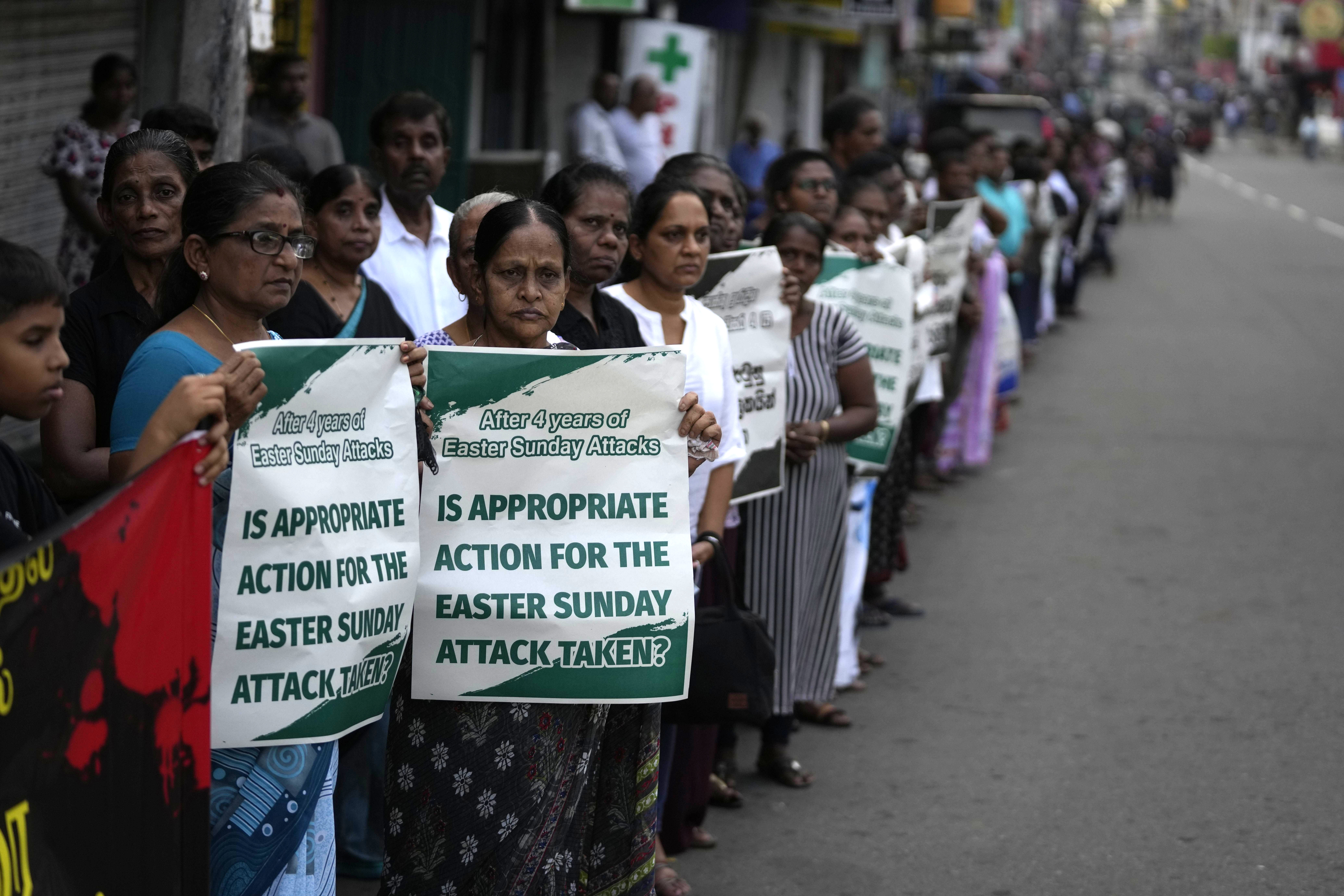 Sri Lankan Catholics hold banners standing on the side of a road during a silent march to mark the fourth year commemoration of the 2019 Easter Sunday bomb attacks on Catholic Churches, in Colombo, Sri Lanka