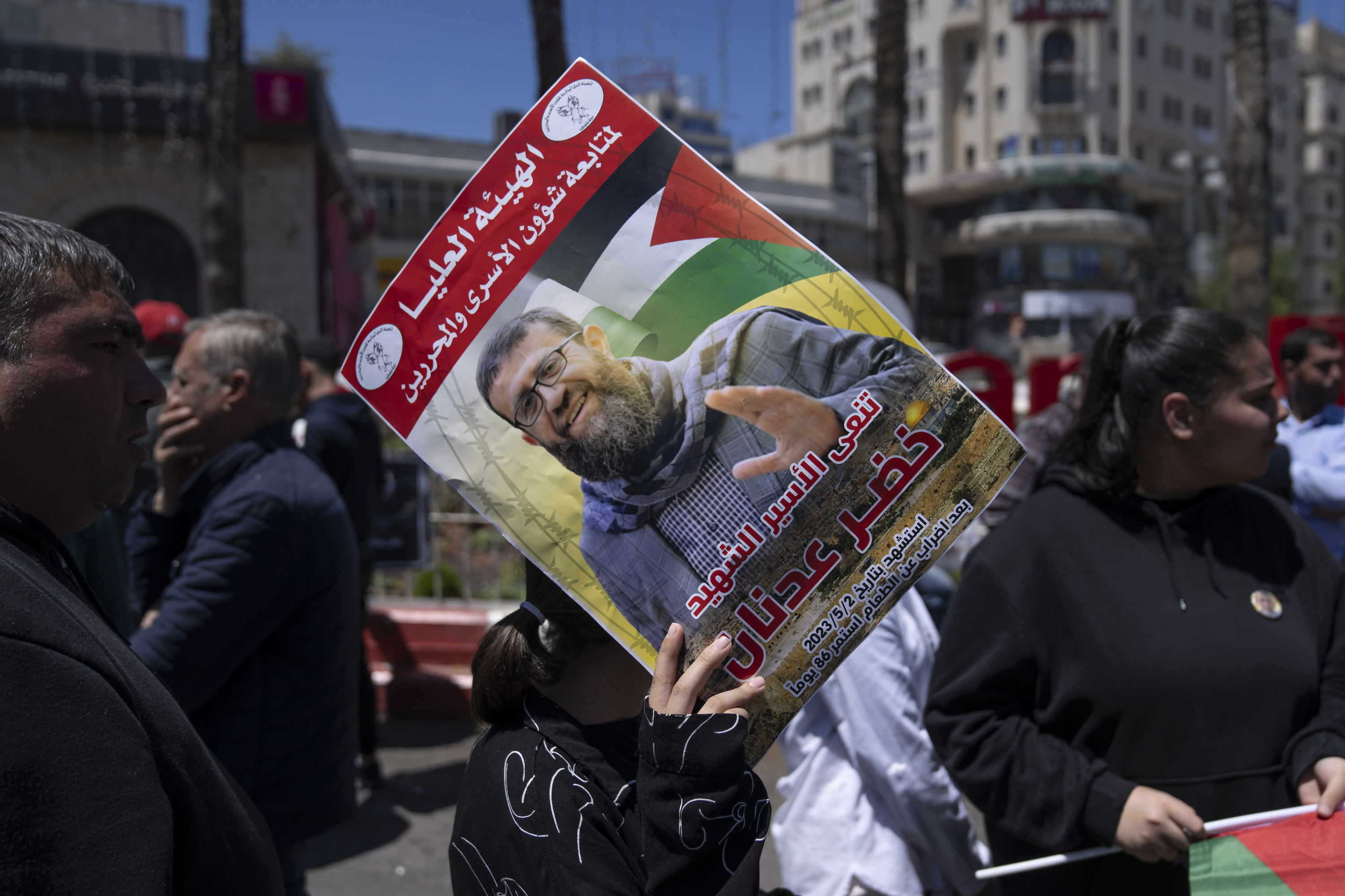 A Palestinian woman holds a poster with a picture of Khader Adnan during a protest in the occupied West Bank city of Ramallah