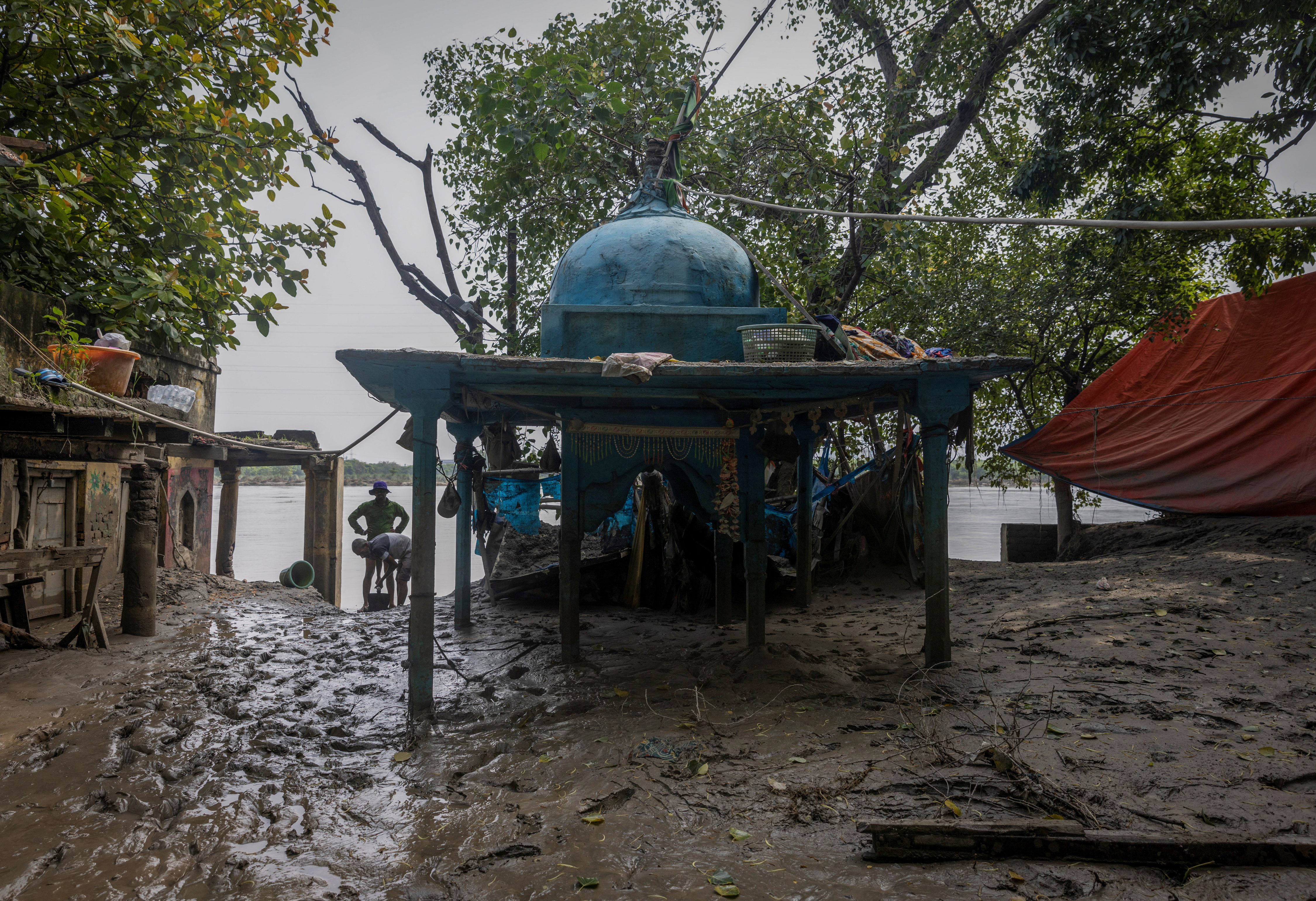 People clean the mud outside their house after flood water recedes from a residential area that was flooded by the overflowing Yamuna River in New Delhi