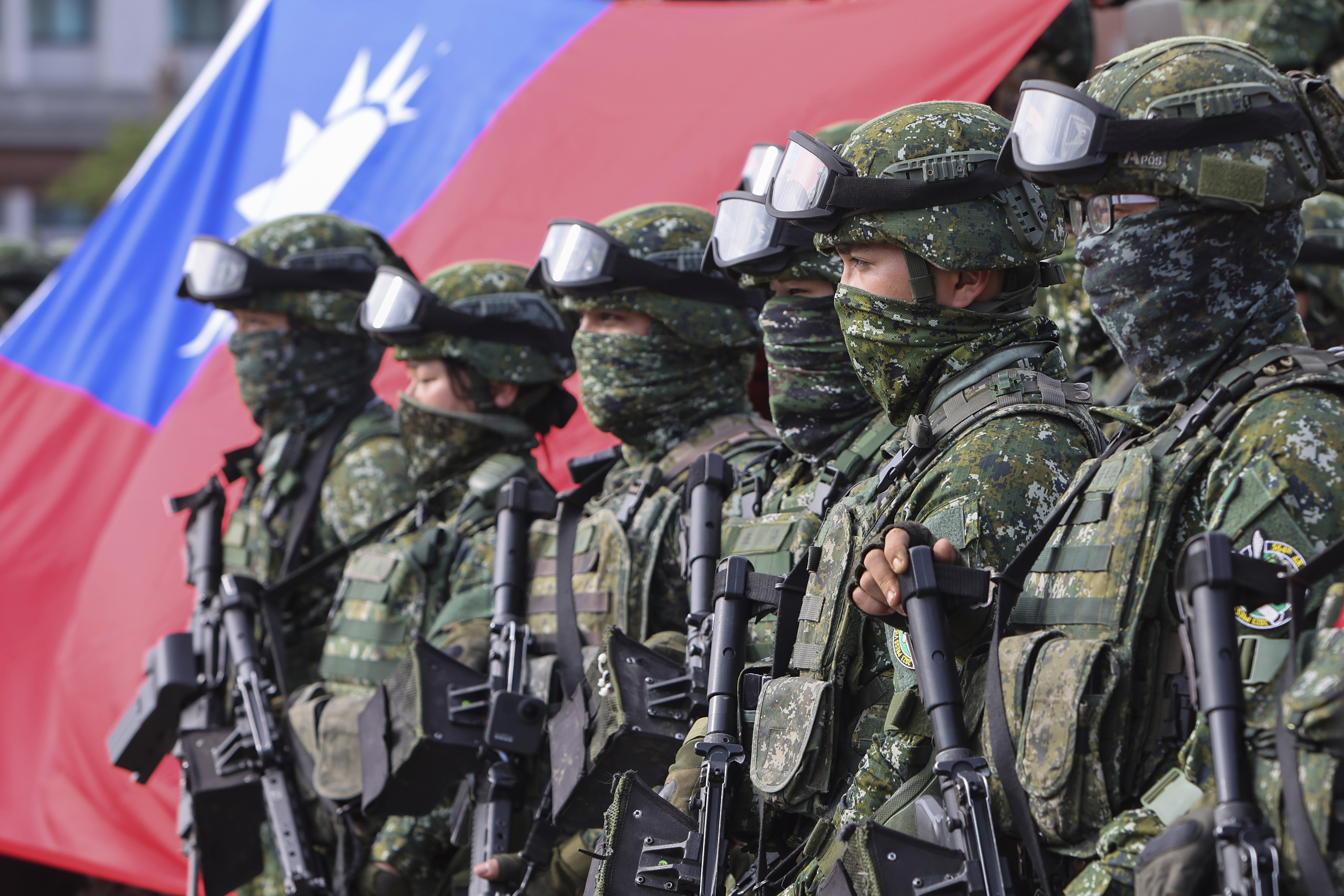 Taiwanese soldiers lining up in front of a Taiwan flag in battle dress