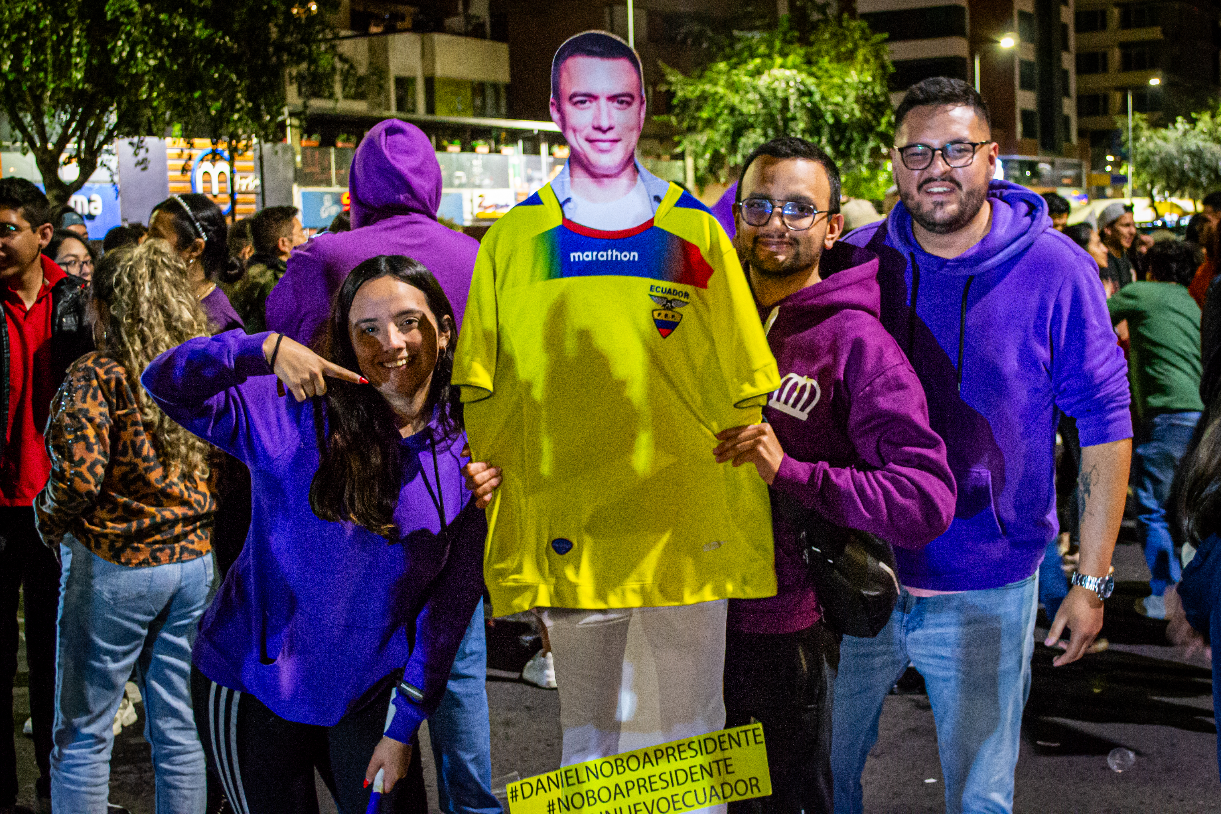A woman points to a cardboard cutout of Daniel Noboa wearing a yellow jersey.
