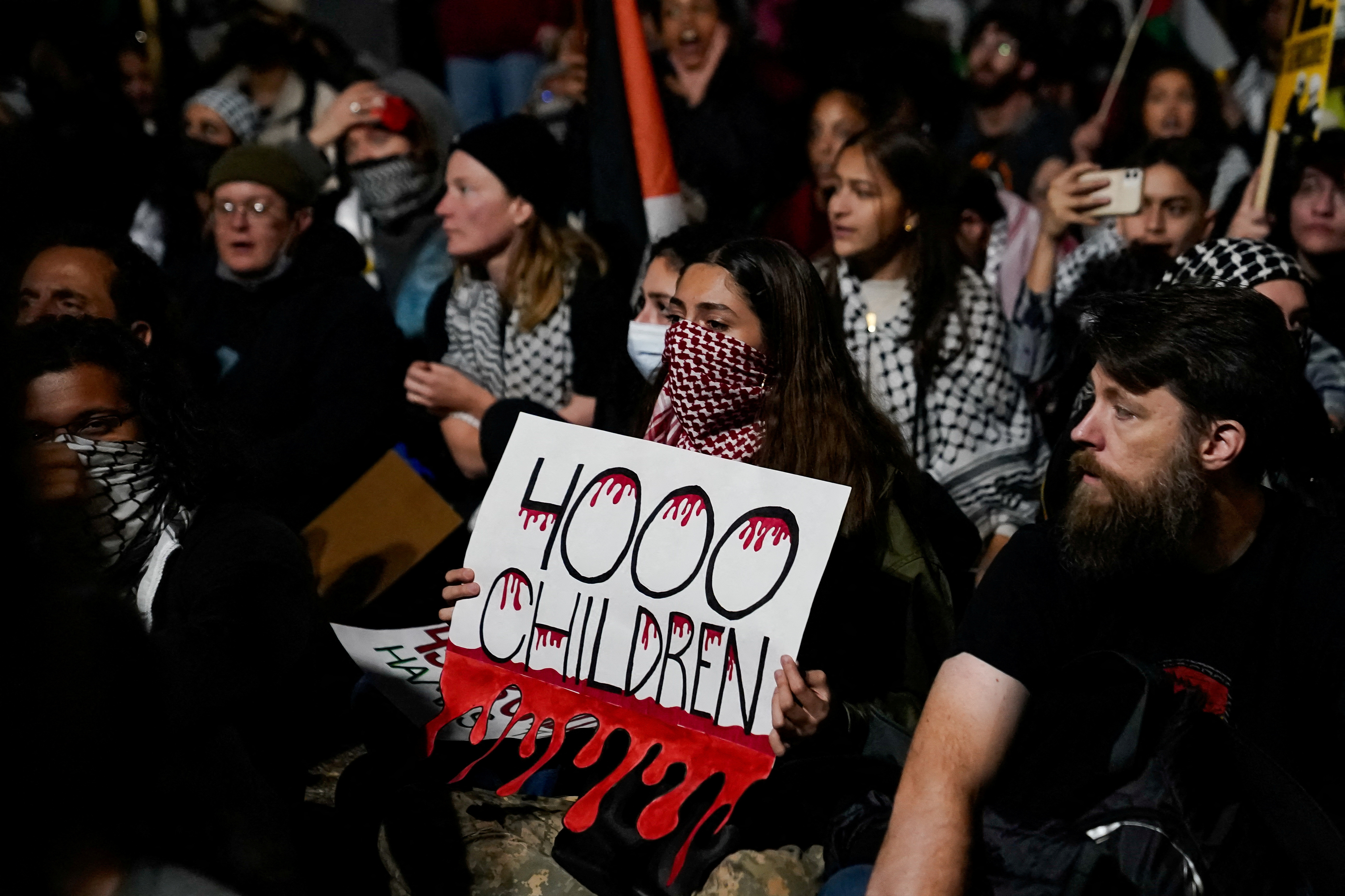 Masked protester hold signs that says '4,000 children'