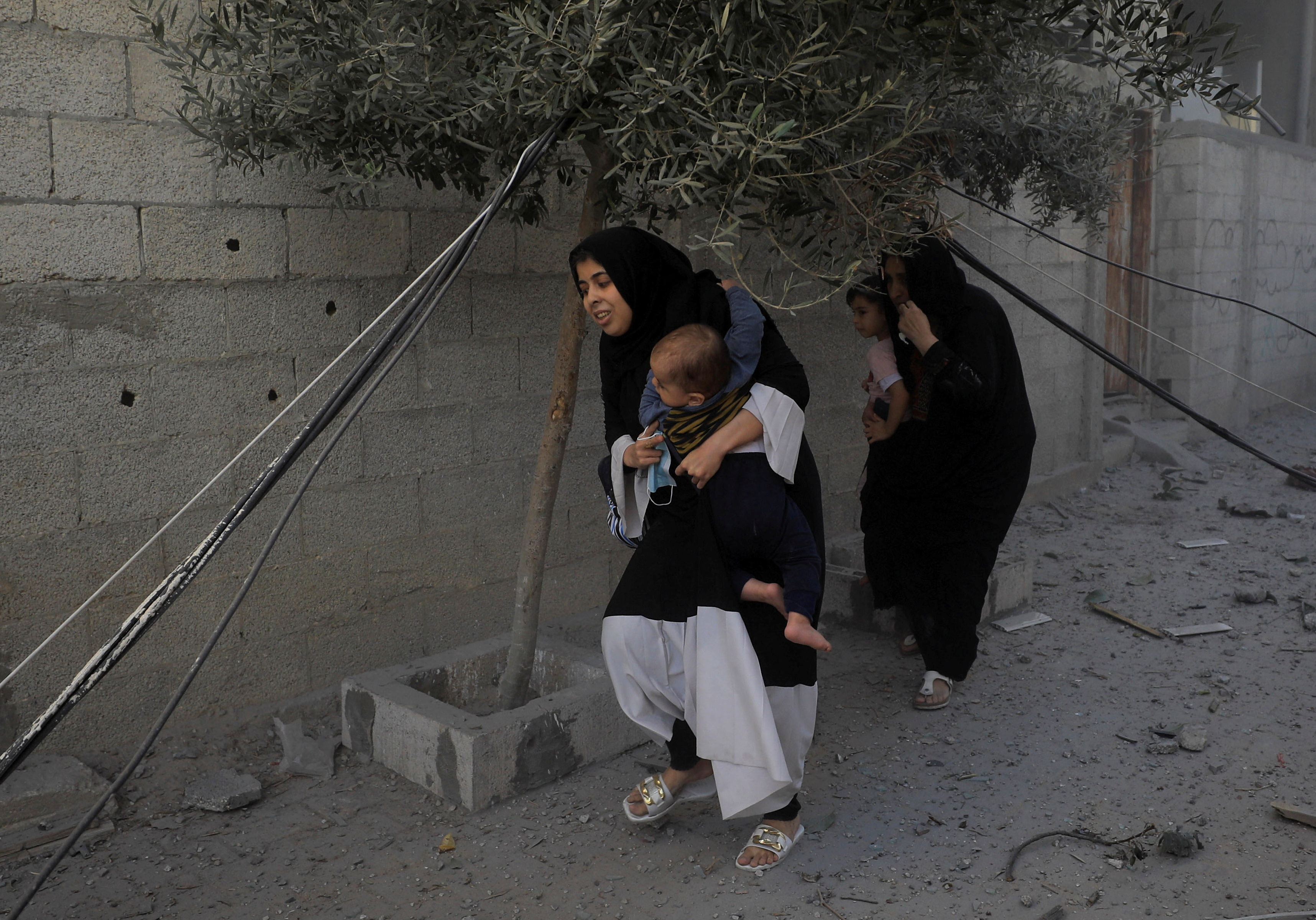 Palestinians evacuate the site of Israeli strikes on houses, amid the ongoing conflict between Israel and Palestinian Islamist group Hamas, in Maghazi refugee camp in the central Gaza Strip
