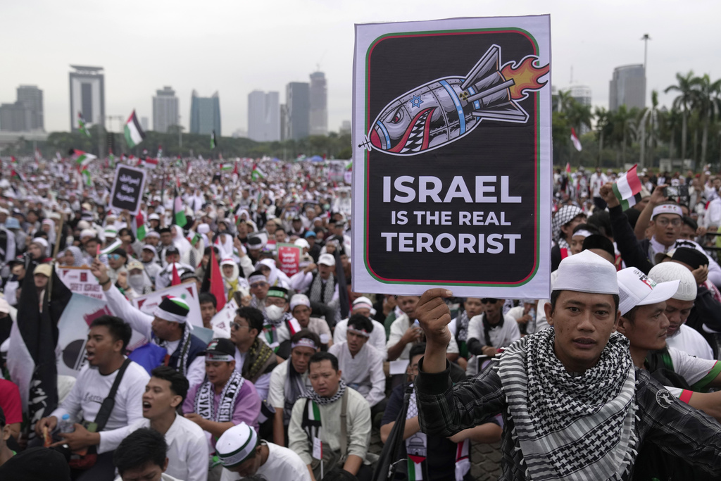 A man holds a poster during a rally in support of the Palestinians in Gaza, at the National Monument in Jakarta, Indonesia, Sunday, Nov. 5, 2023. (AP Photo/Dita Alangkara)
