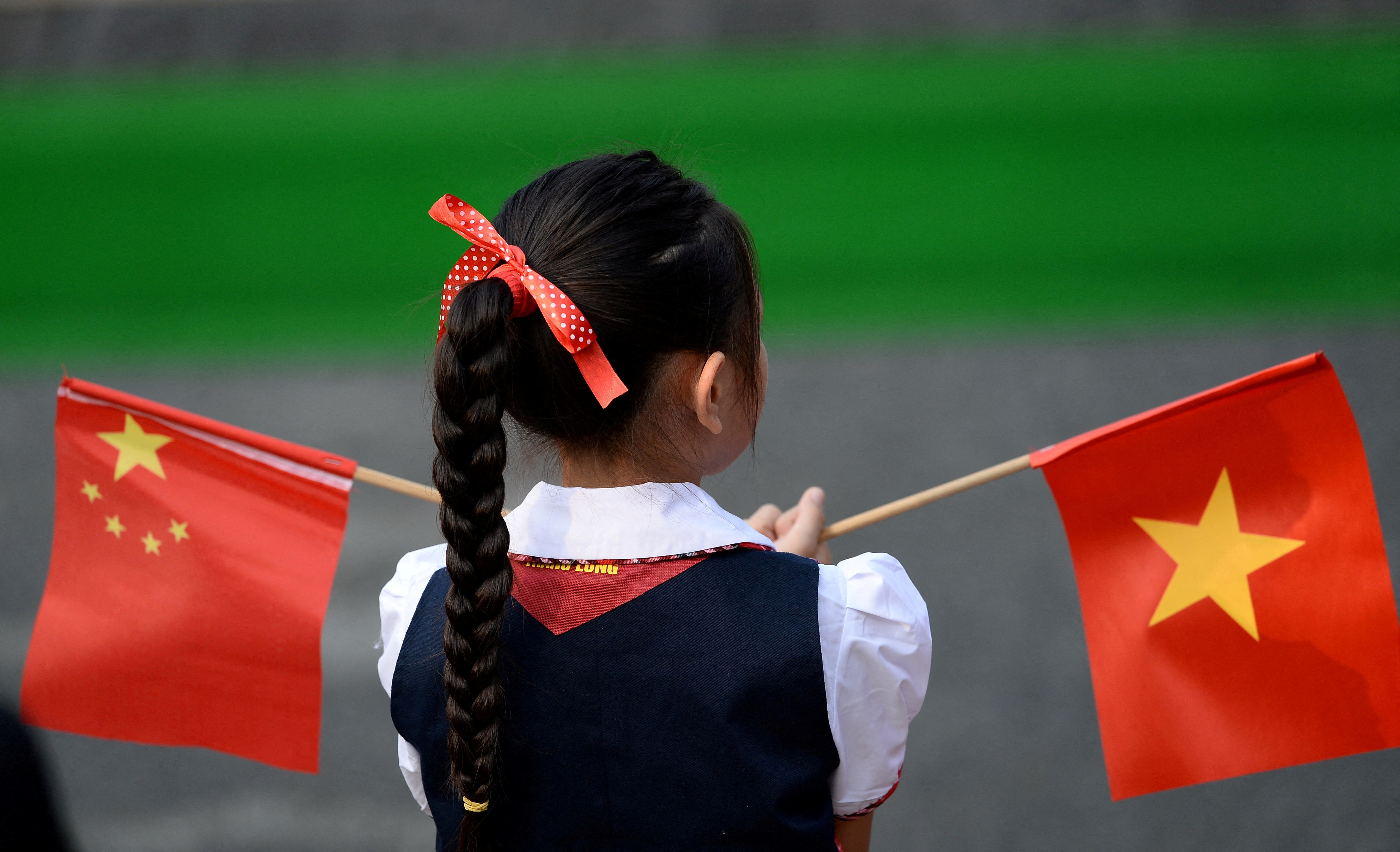A girl holds the Chinese and Vietnamese flags