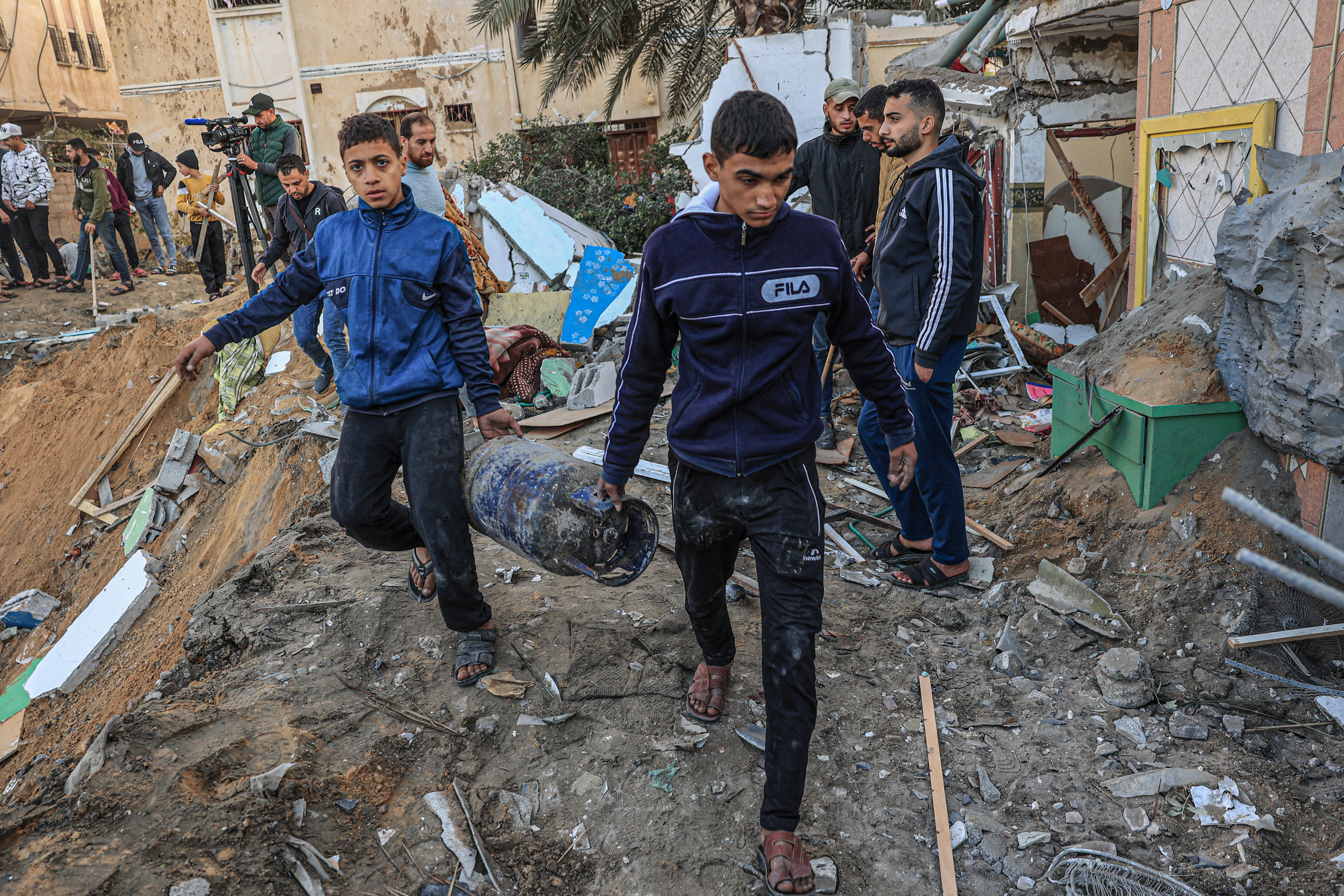 People search building rubble for items to salvage following an early morning Israeli strike in Rafah in the southern Gaza Strip on December 12