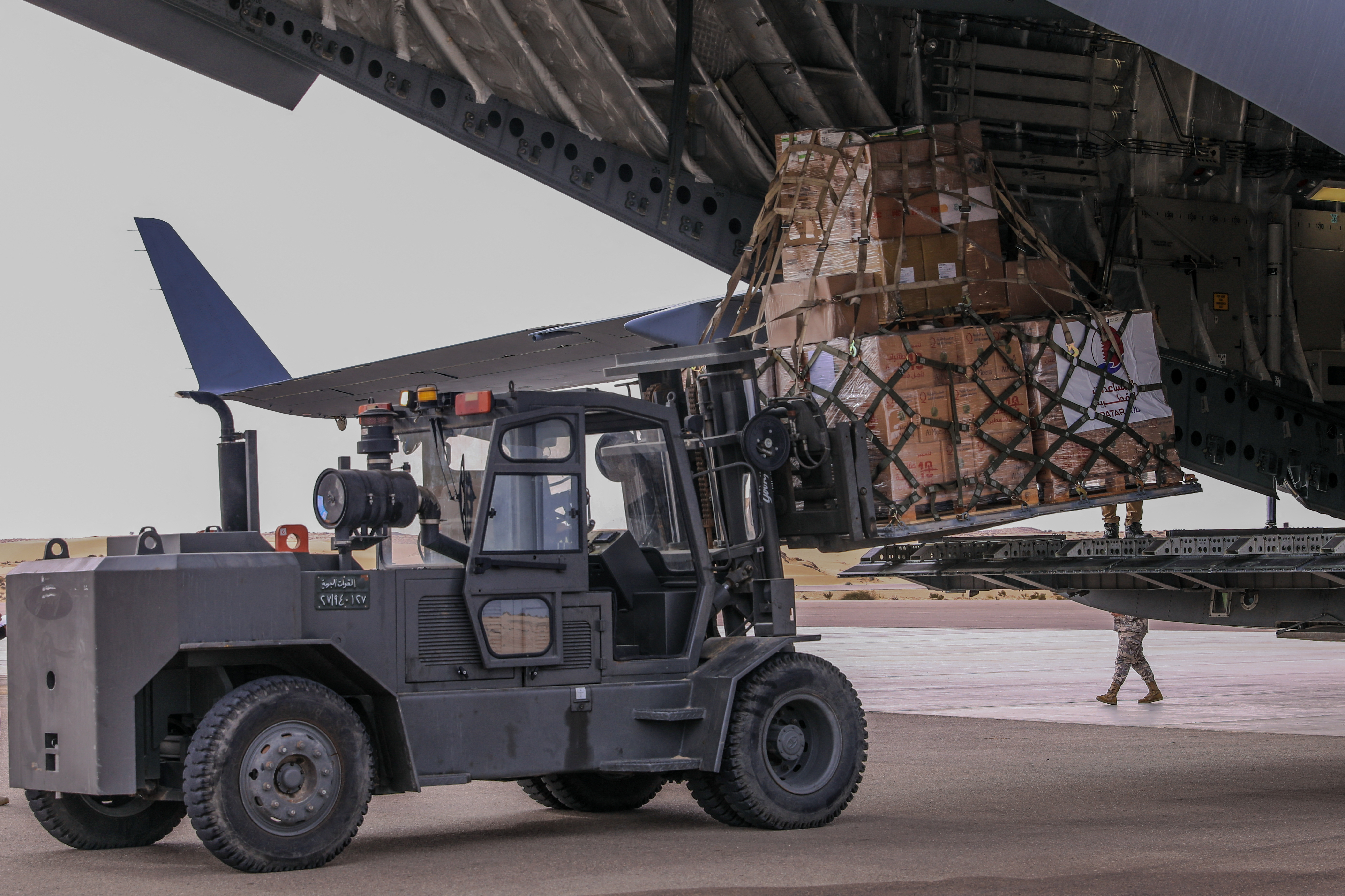 Airport workers unload crates with aid delivered from Qatar, destined for Gaza