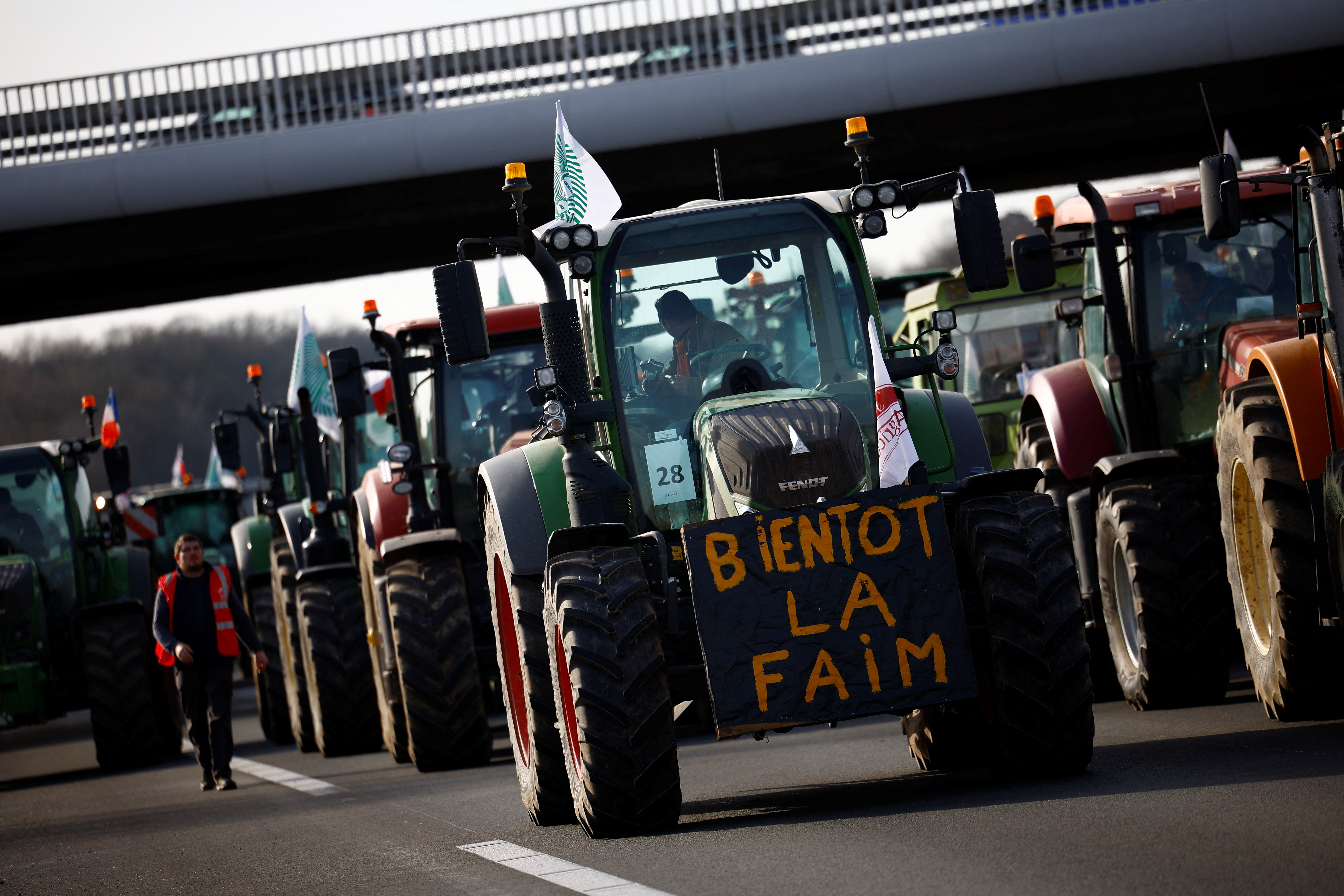 French farmers drive their tractors on a highway, in Longvilliers. The placard reads, ‘Soon hunger’