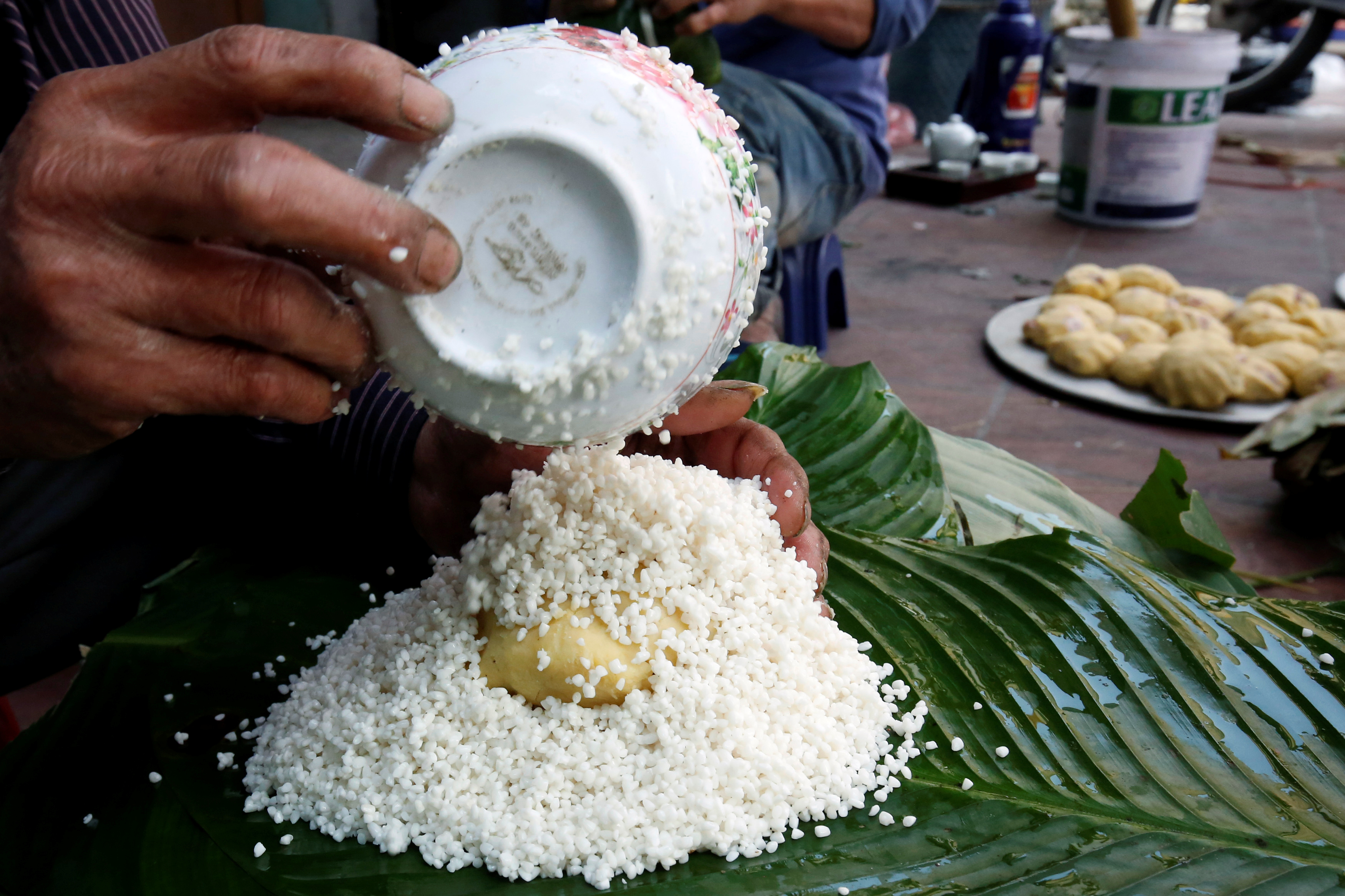 A man wraps banh chung, or rice cakes, for sale ahead of Tet, the traditional Vietnamese Lunar New Year festival, in Tranh Khuc village, outside Hanoi, Vietnam
