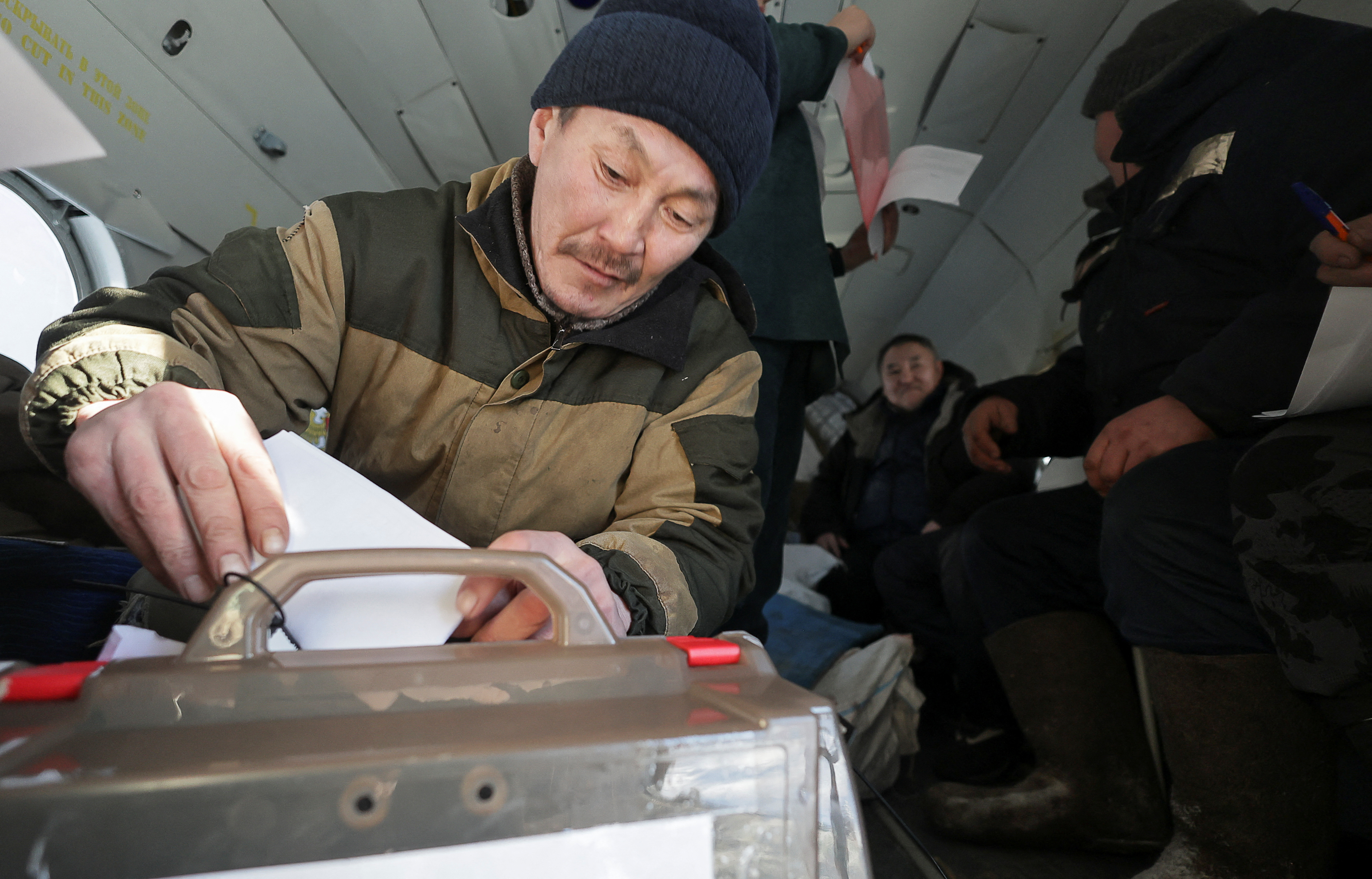 Reindeer herder Dmitry Neustroyev, 50, casts his ballot inside a helicopter during early voting in Russia's presidential election, as members of an electoral commission visit a remote farm in the Sakha Republic, also known as Yakutia, in the northeastern part of Siberia, Russia, February 29, 2024