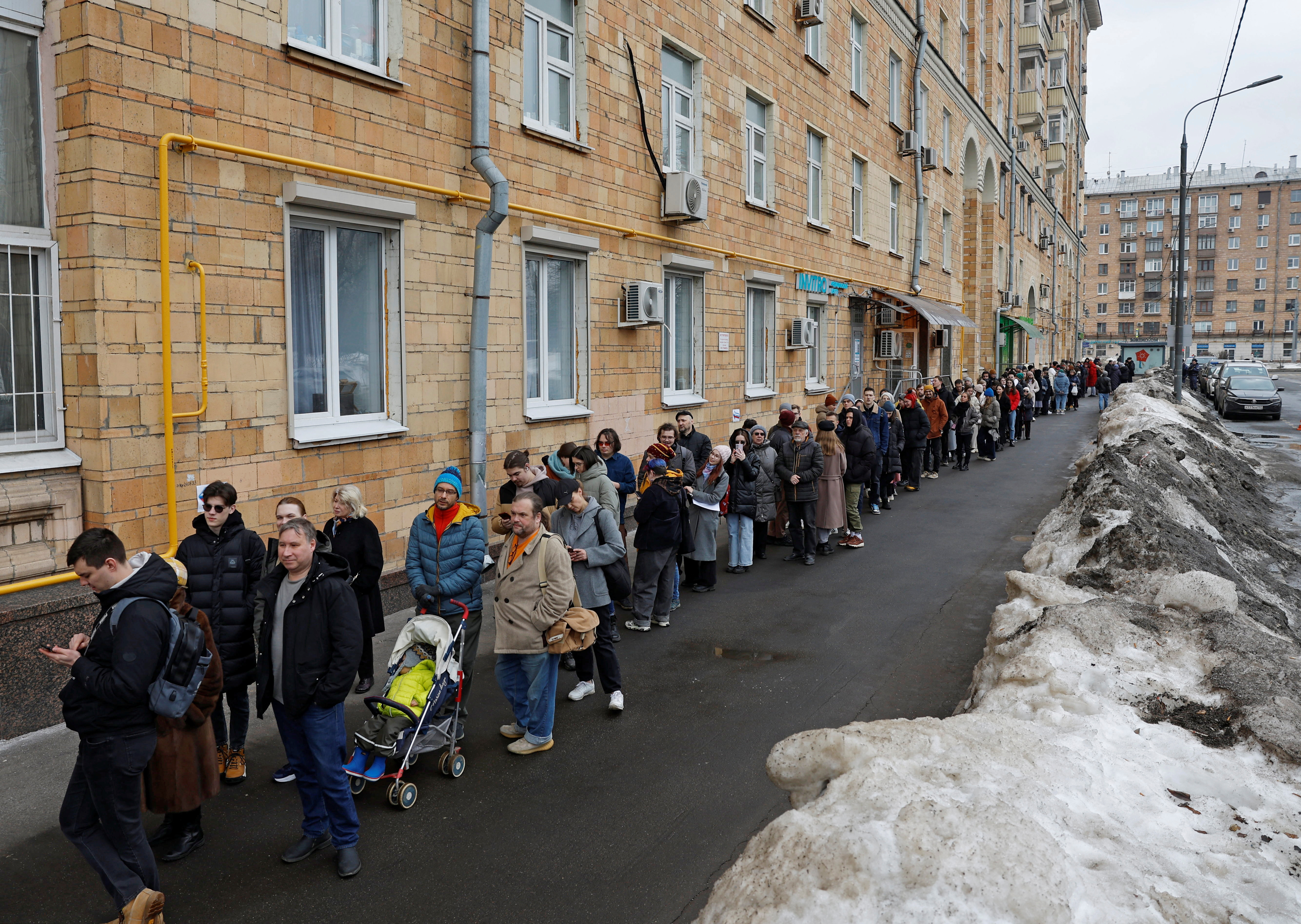 People stand in a line to enter a polling station around noon on the final day of the presidential election in Moscow, Russia, March 17