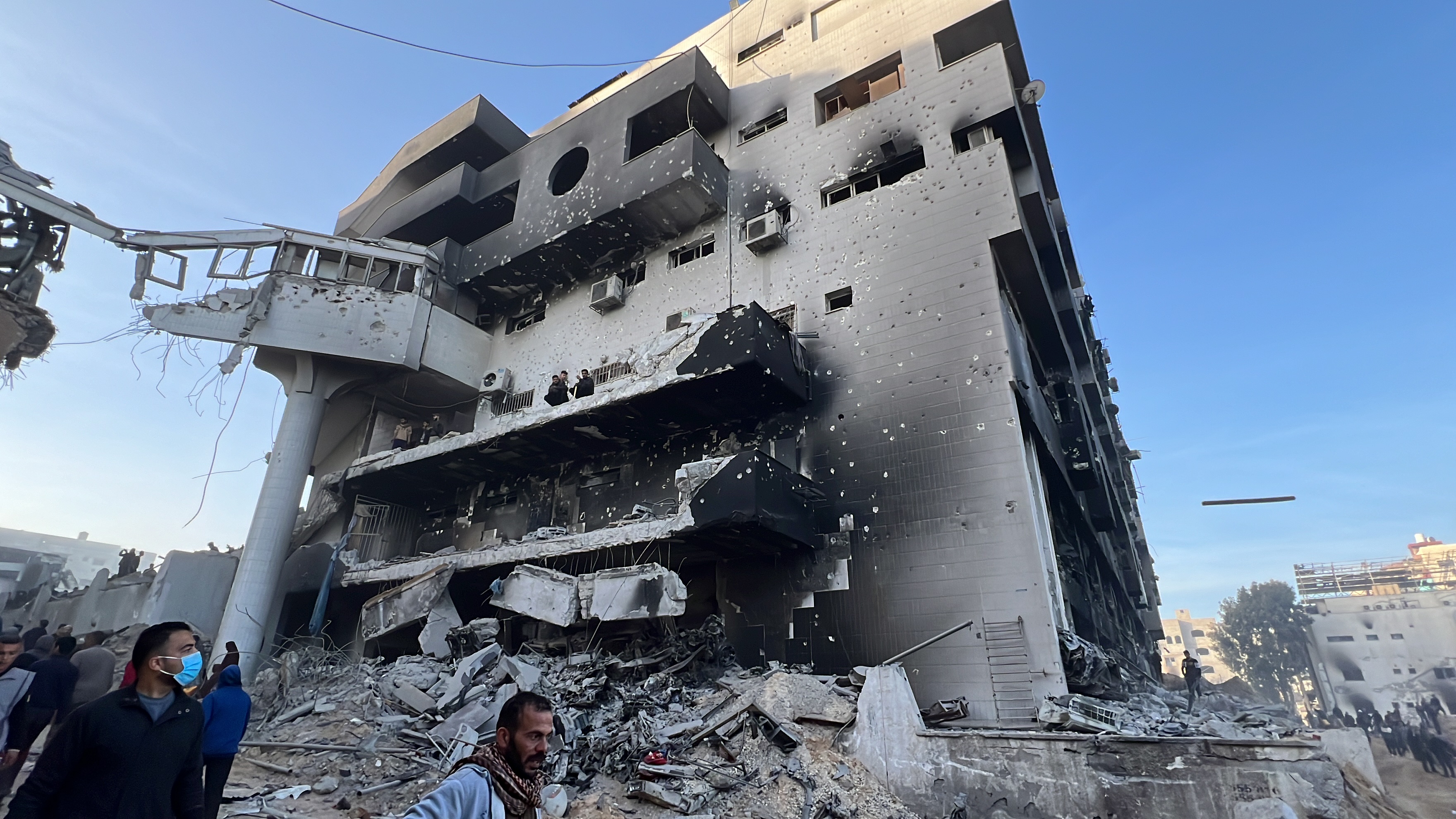 Palestinians gather around the burned and destroyed Al-Shifa Hospital