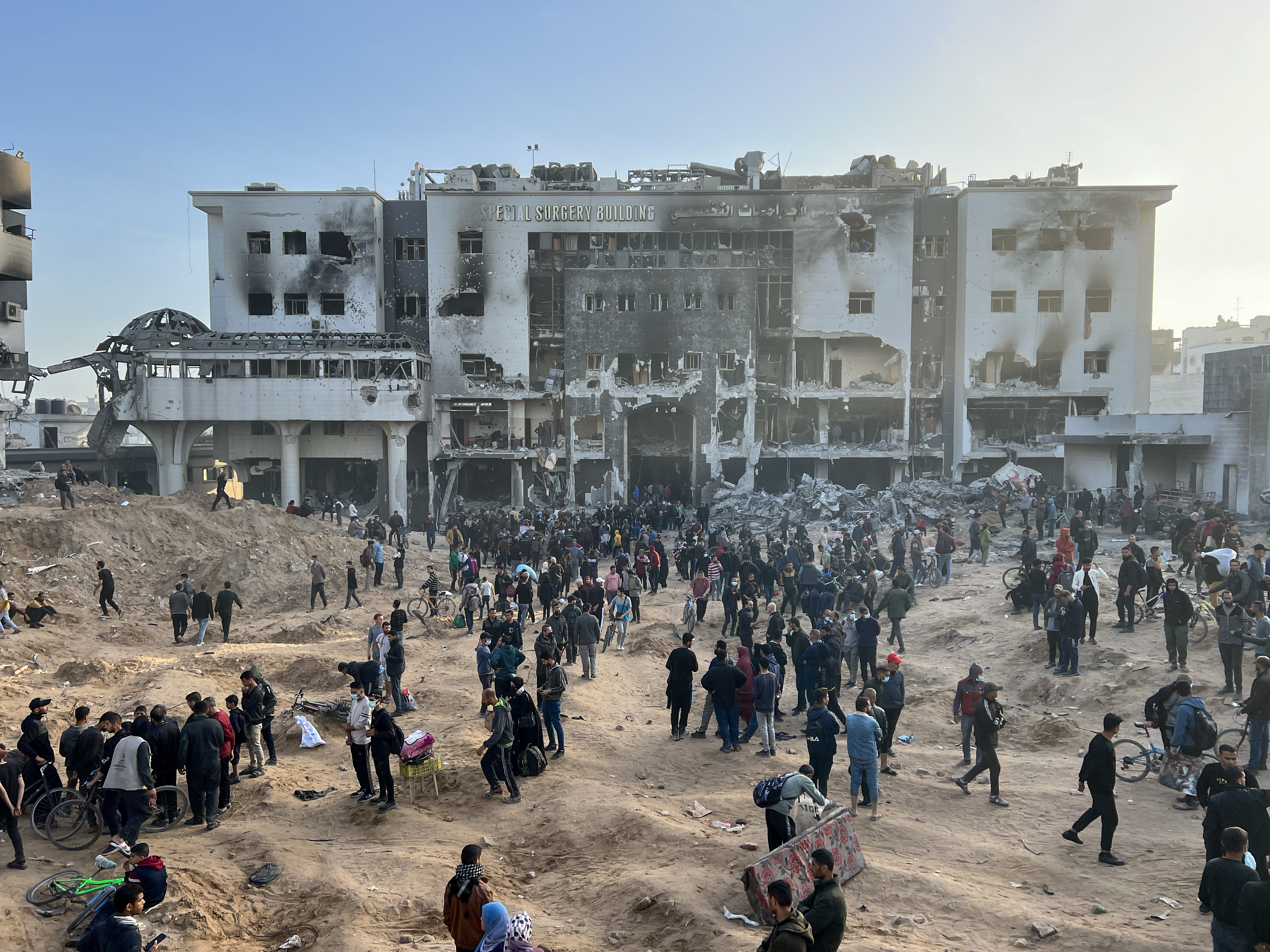 Palestinians gather around the burned and destroyed Al-Shifa Hospital