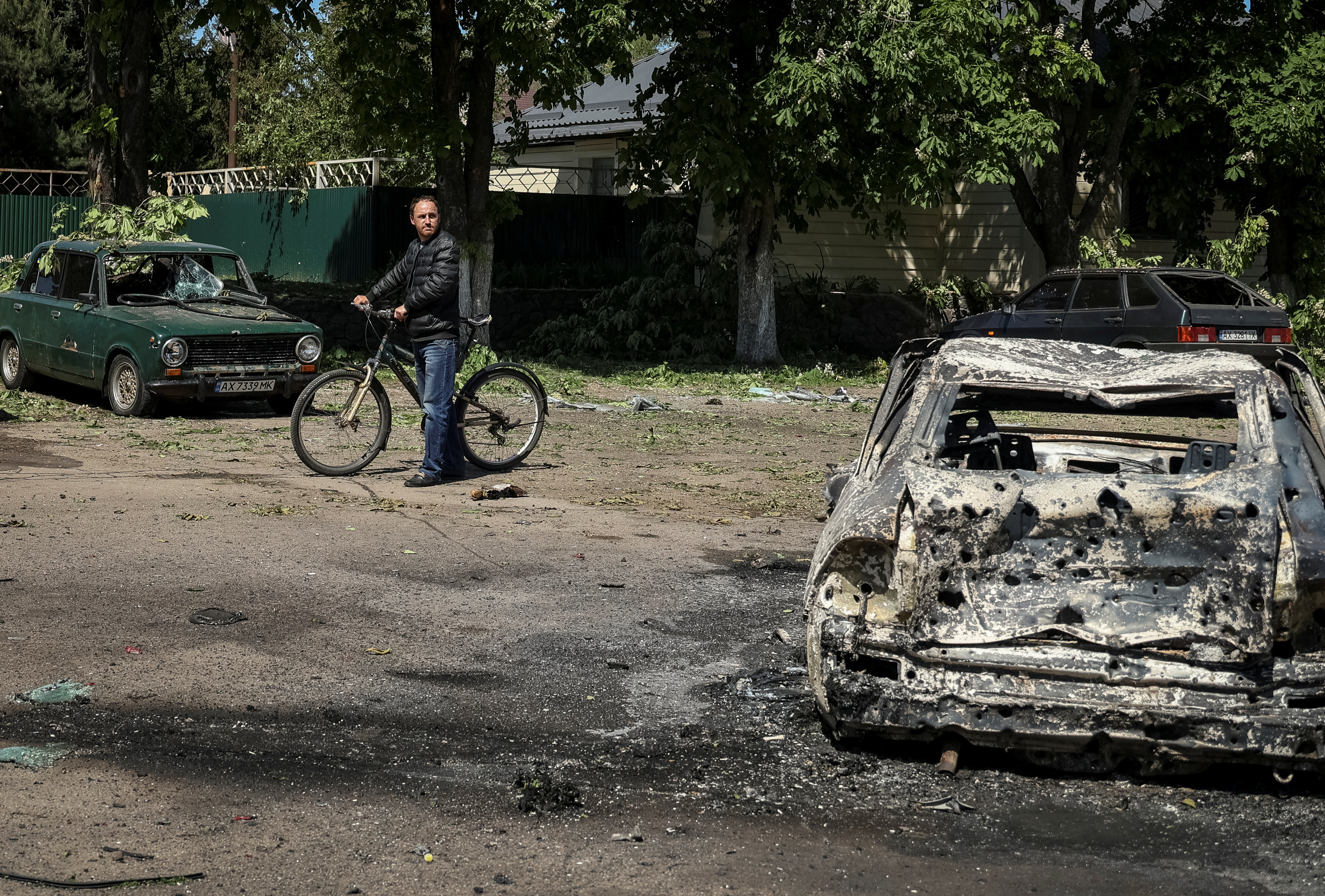 A local resident looks at a destroyed car at a site of a Russian missile strike, amid Russia's attack on Ukraine, in the village of Zolochiv in Kharkiv region, Ukraine May 1, 2024. REUTERS/Sofiia Gatilova