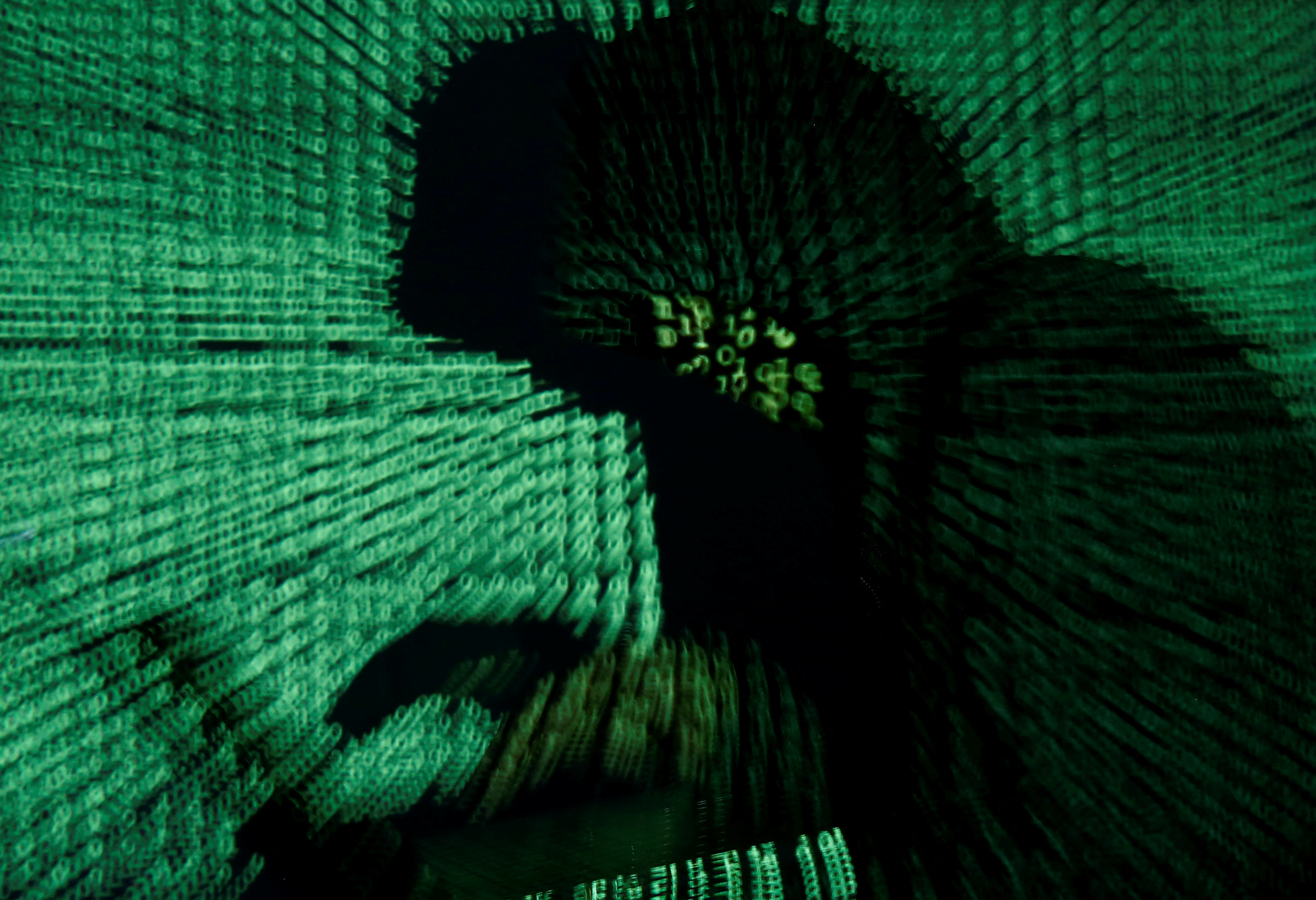 A man holds a laptop computer as cybercode is projected on him in an illustration picture.
