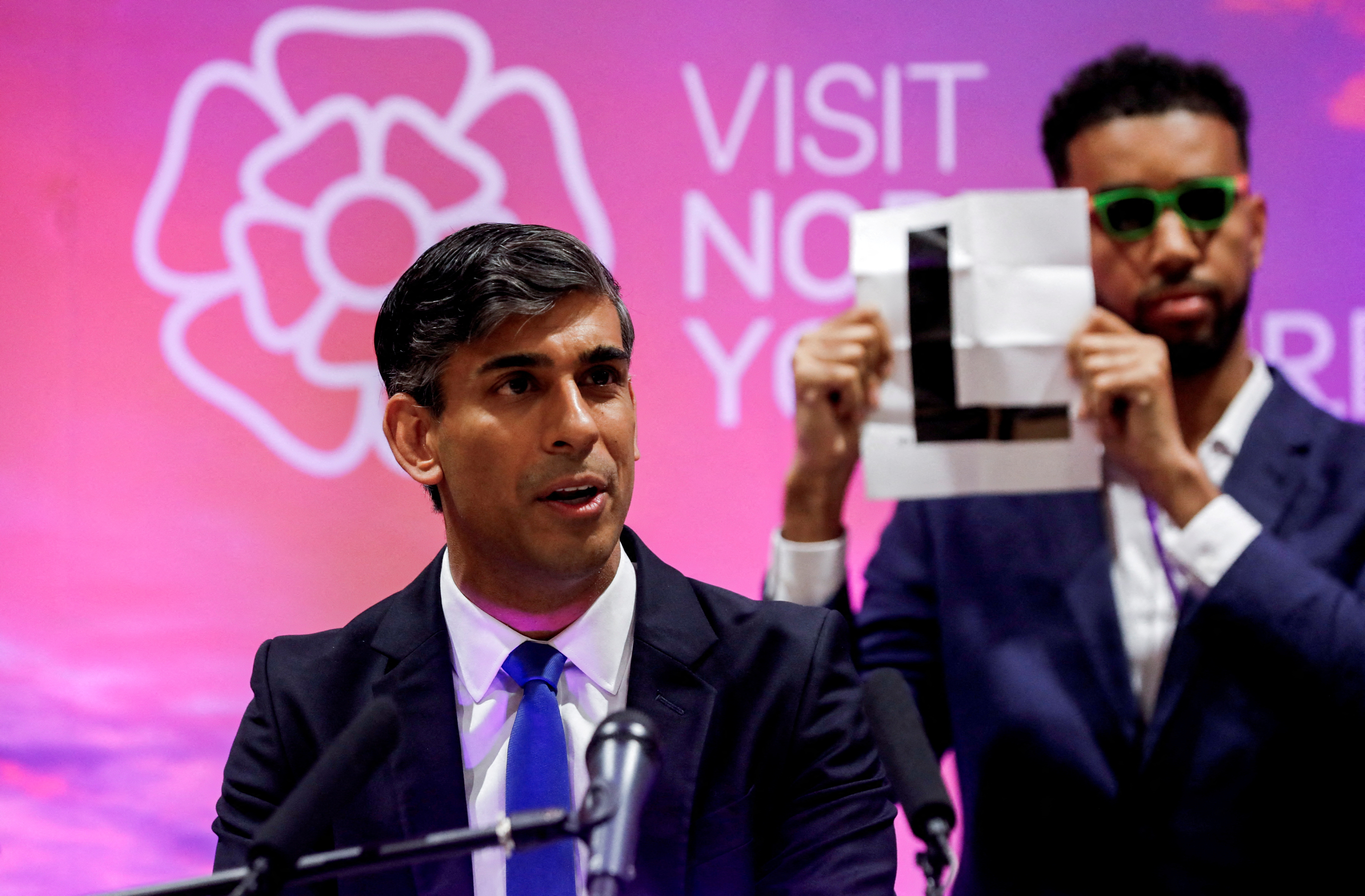 Independent candidate Niko Omilana holds an "L" behind British Prime Minister Rishi Sunak as he speaks after winning his seat at Richmond and Northallerton during the UK election in Northallerton, Britain, July 5, 2024. REUTERS/Temilade Adelaja/Pool
