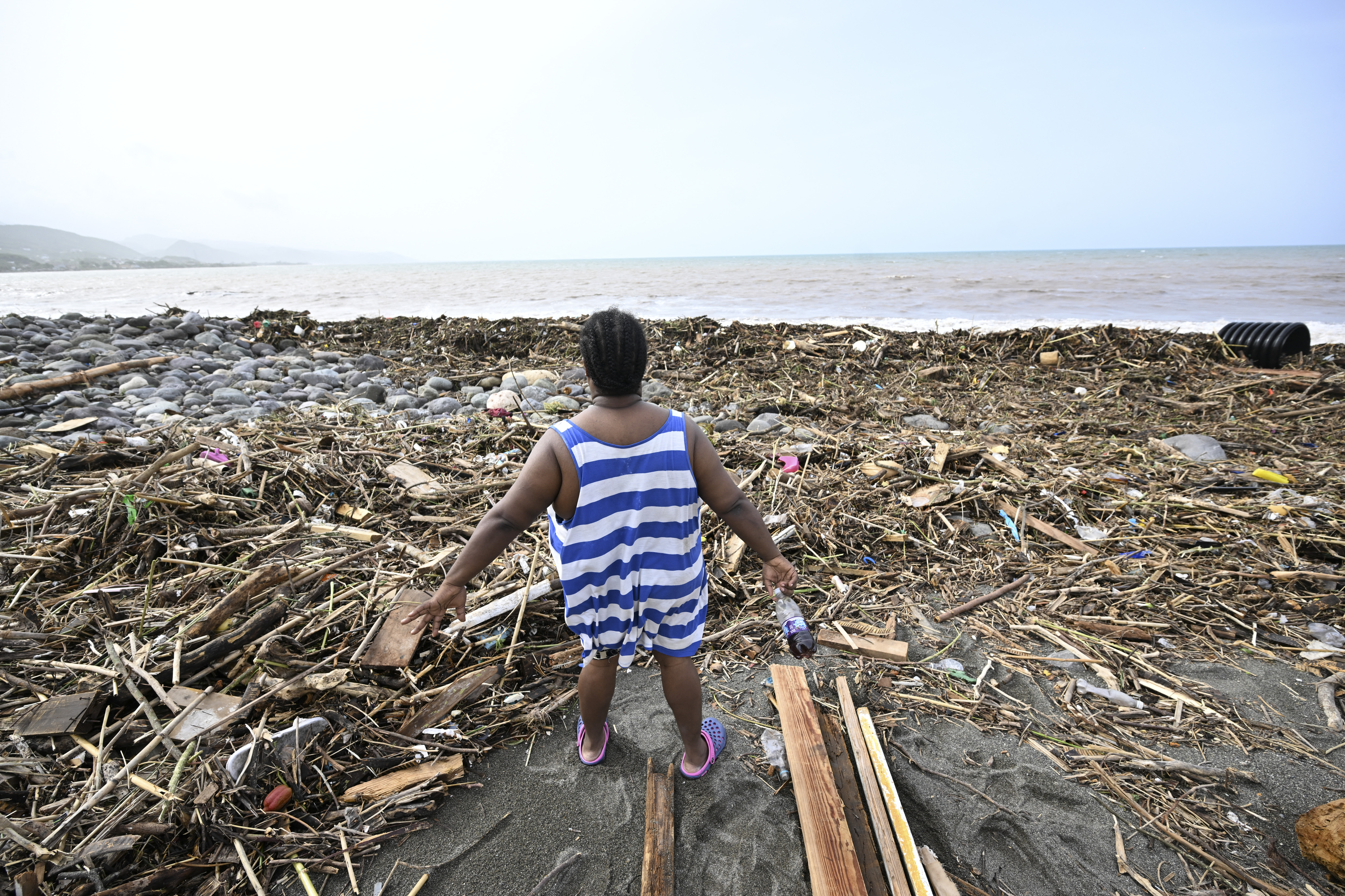 A woman looks at a beach littered with rubbish at Bull Bay, Jamaica, in the aftermath of Hurricane Beryl on July 4, 2024