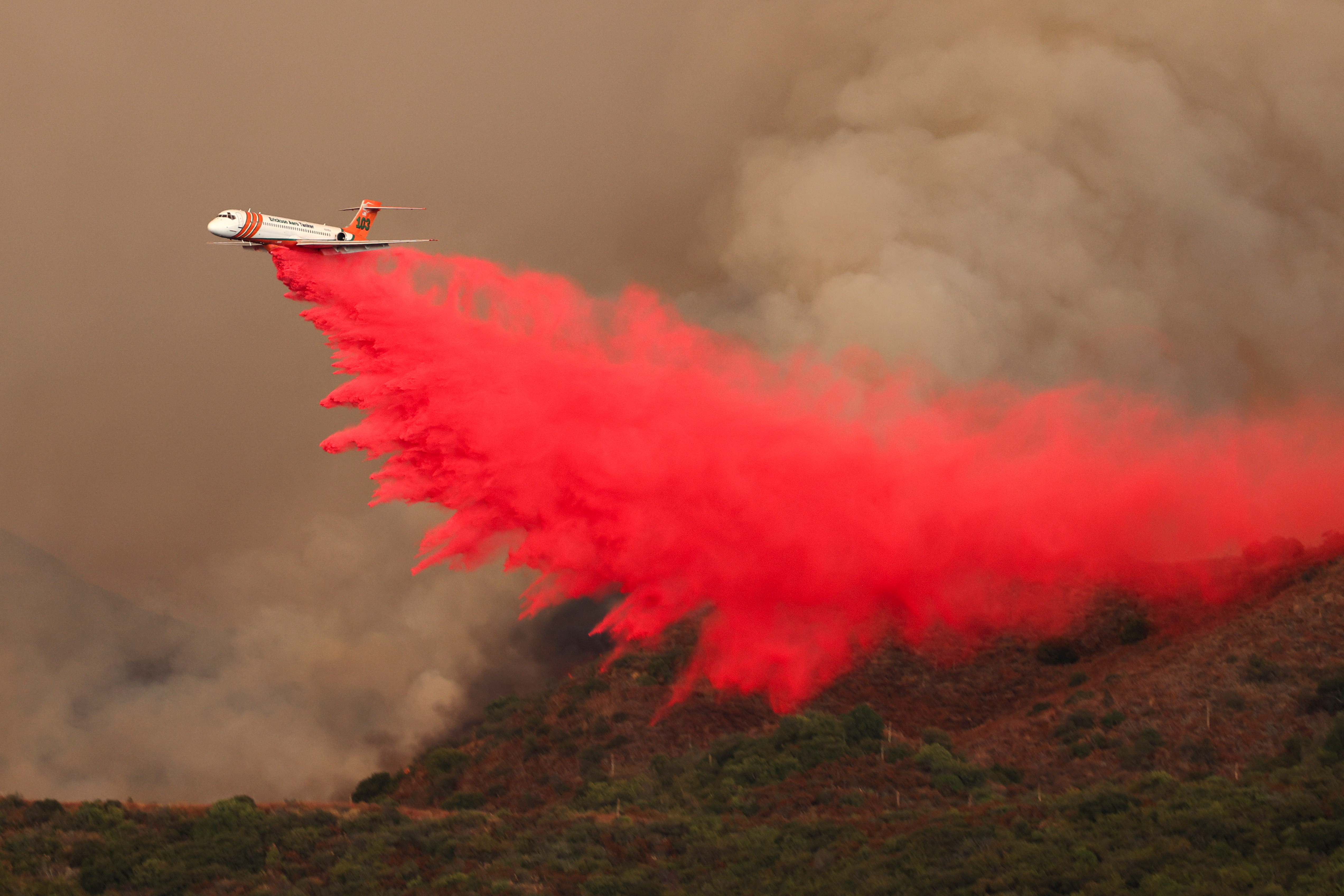 An aerial tanker combats the Airport Fire, a wildfire burning in the hills of Orange County