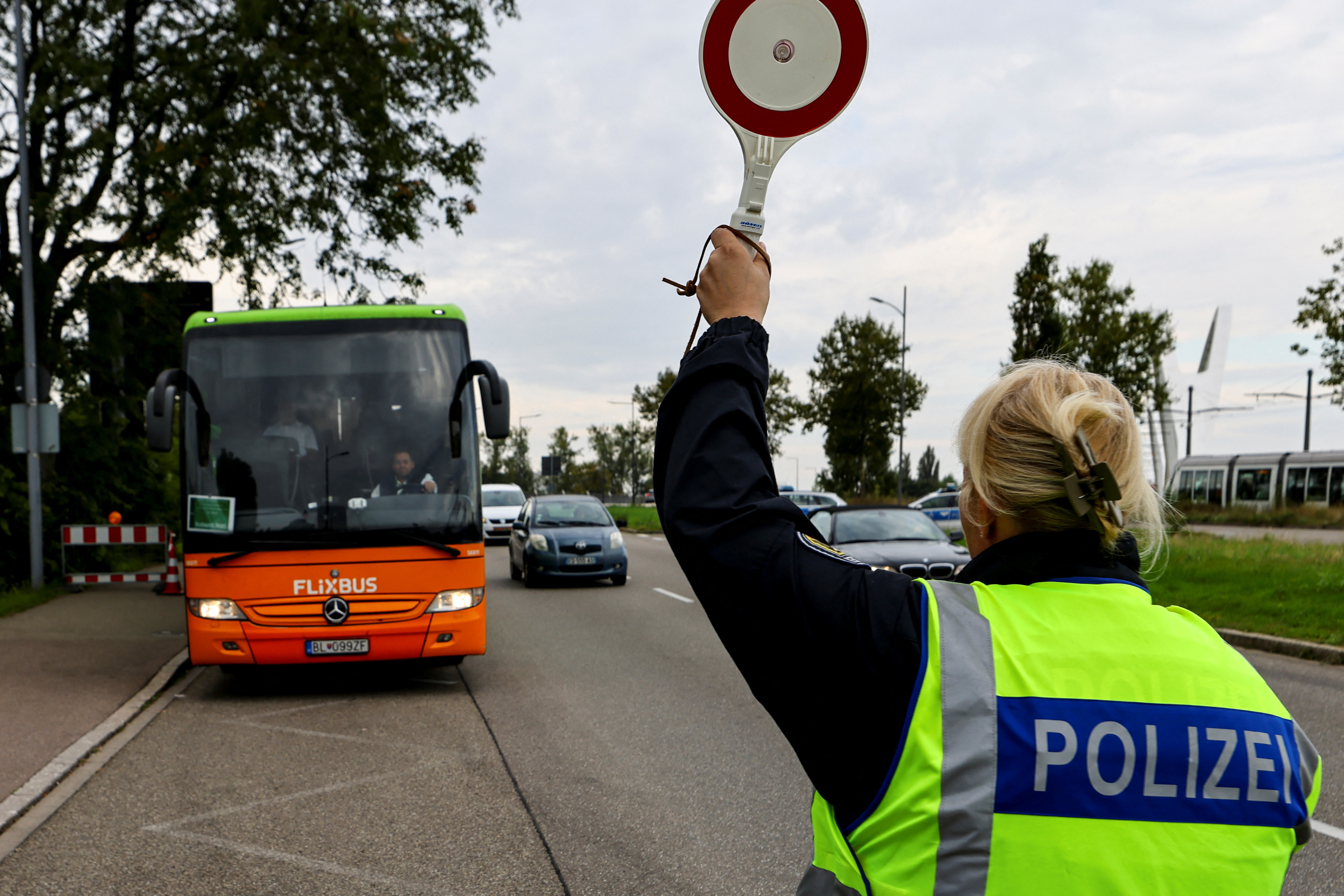 A German police officer stops a bus at a border with France