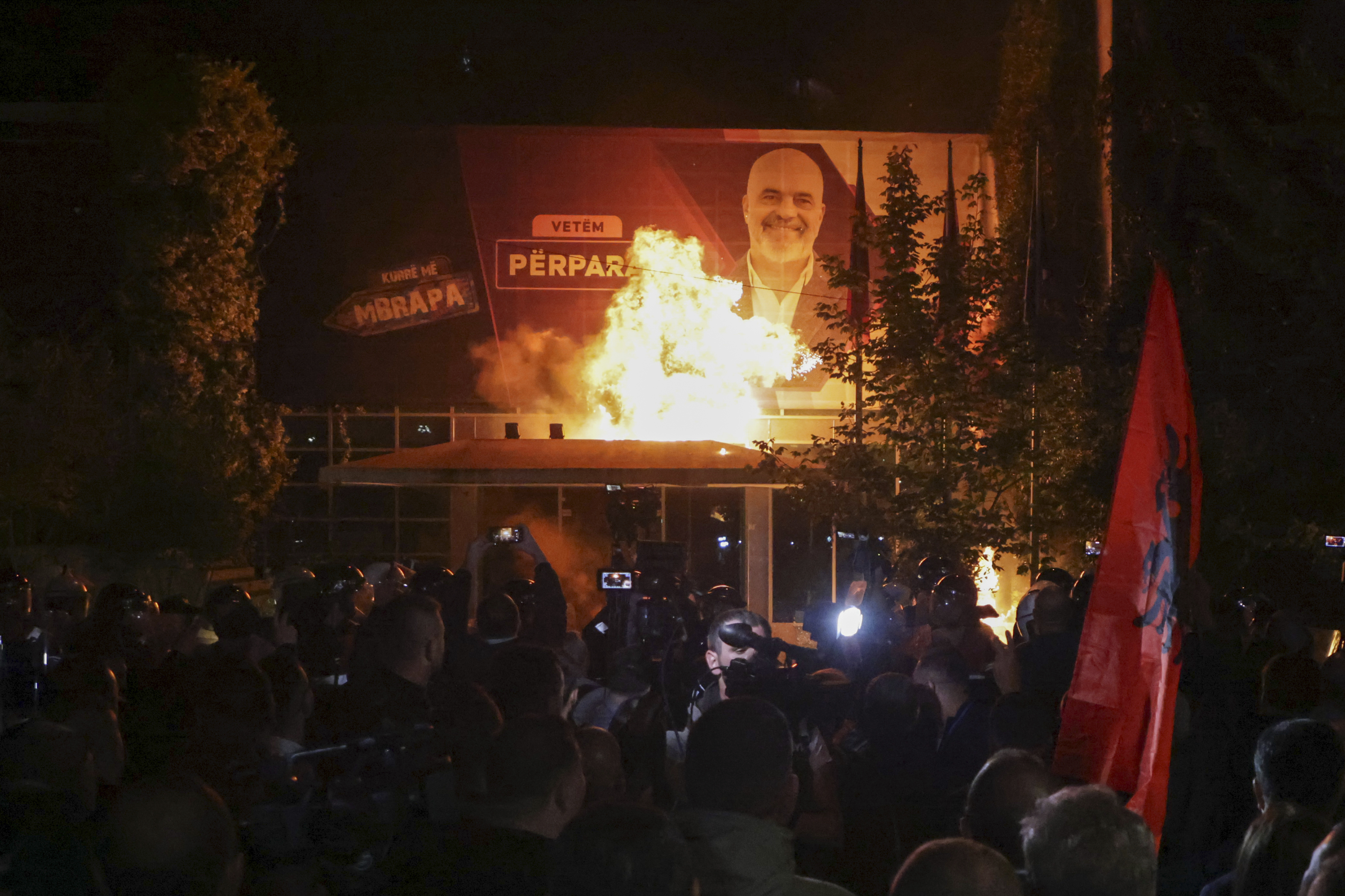 Fire burns behind a riot police cordon and in front of a poster depicting the Albania Prime minister Edi Rama during an anti-government rally set up by the opposition, in Tirana, Albania, Monday, Oct. 7