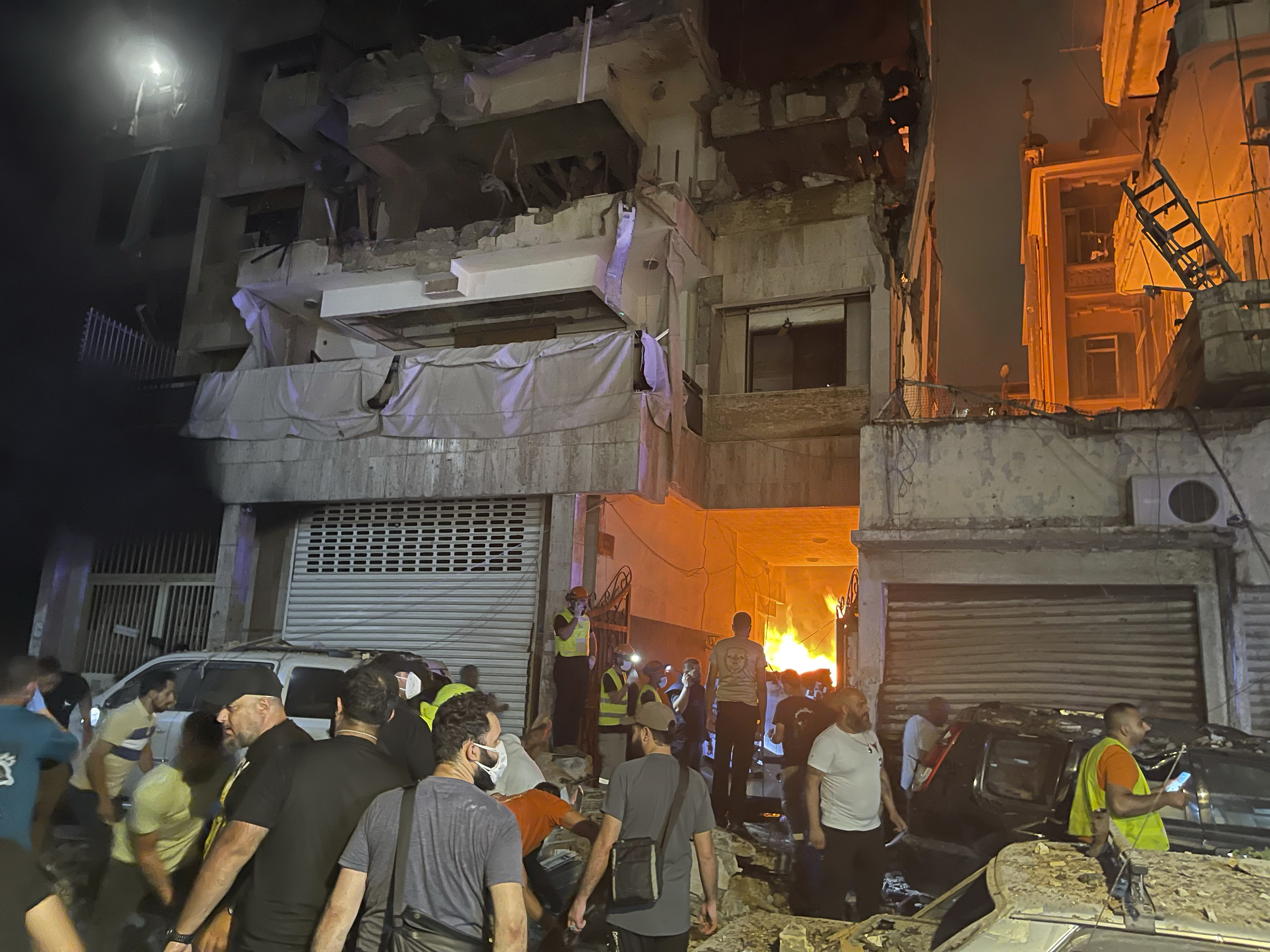 People gathering in front a destroyed building hit by an Israeli airstrike in central Beirut, Lebanon, Thursday, Oct. 10