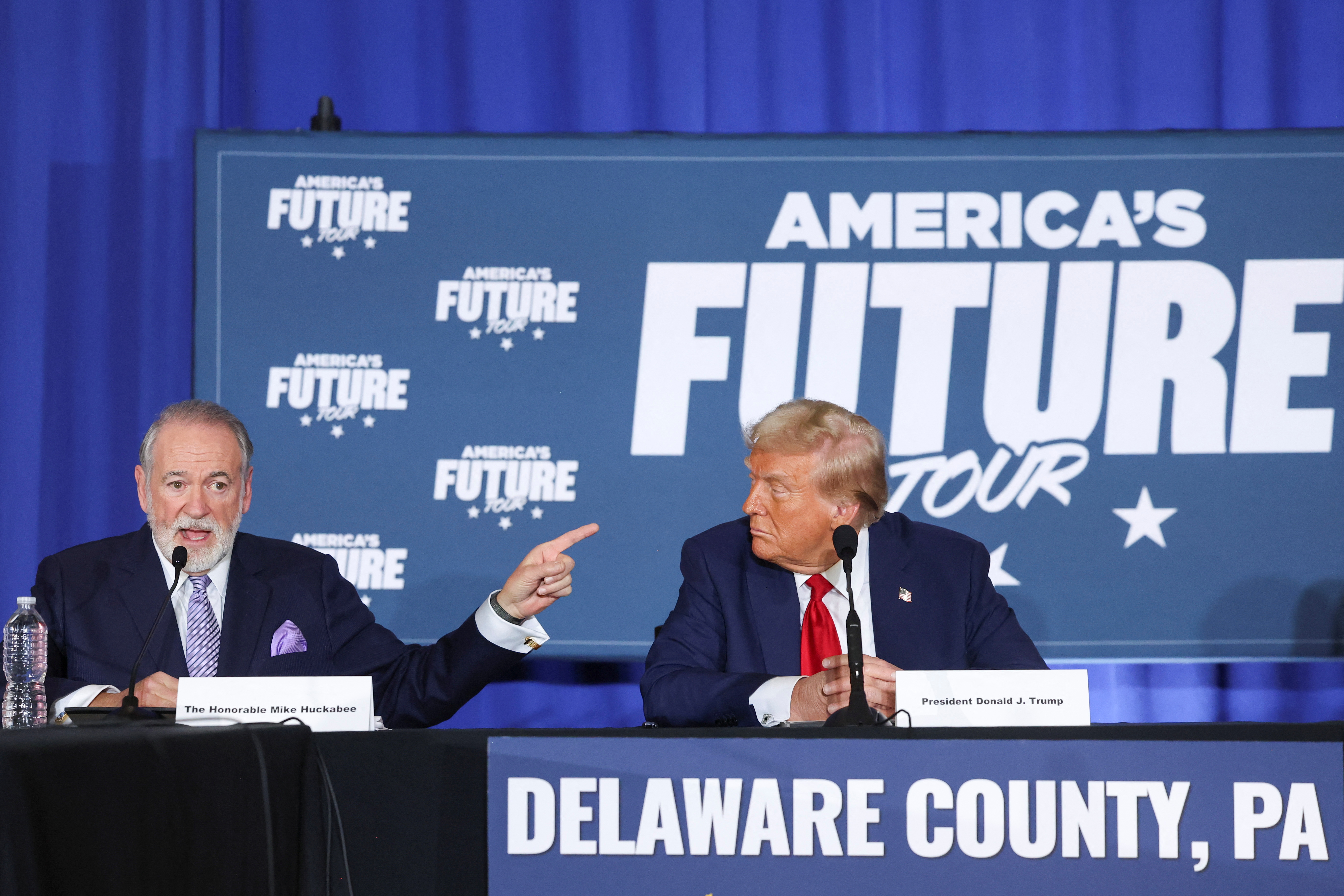 Mike Huckabee and Donald Trump sit side-by-side during a panel 