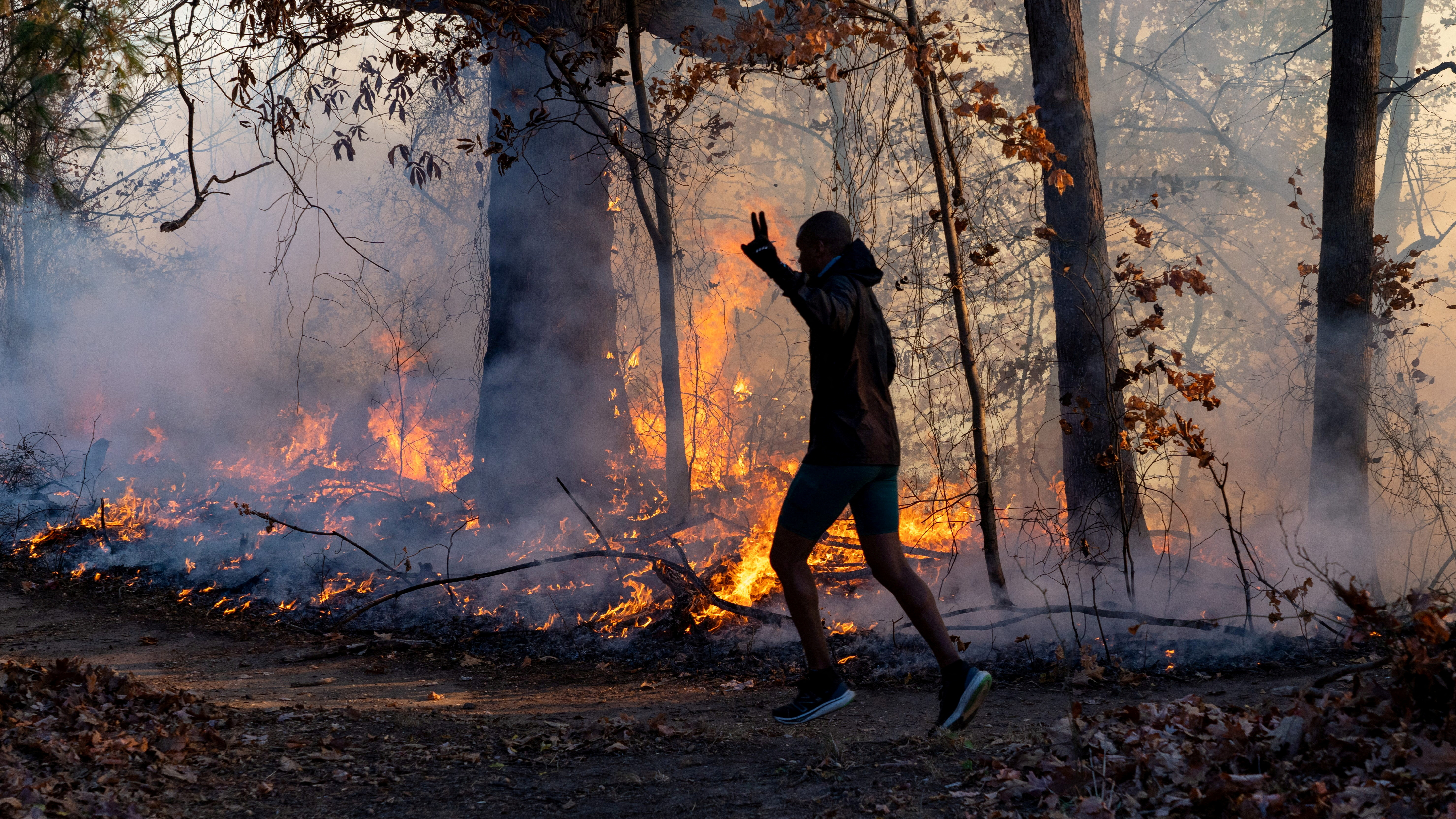 A morning jogger gestures as he runs past a fire lit by members of the New Jersey Forest Fire Service as part of back burning efforts alongside Palisades Interstate Parkway in Englewood Cliffs, New Jersey, U.S., November 8, 2024. Julian Leshay Guadalupe/NorthJersey.com / USA TODAY NETWORK via REUTERS ATTENTION EDITORS - THIS IMAGE HAS BEEN SUPPLIED BY A THIRD PARTY. NO RESALES. NO ARCHIVES. TPX IMAGES OF THE DAY