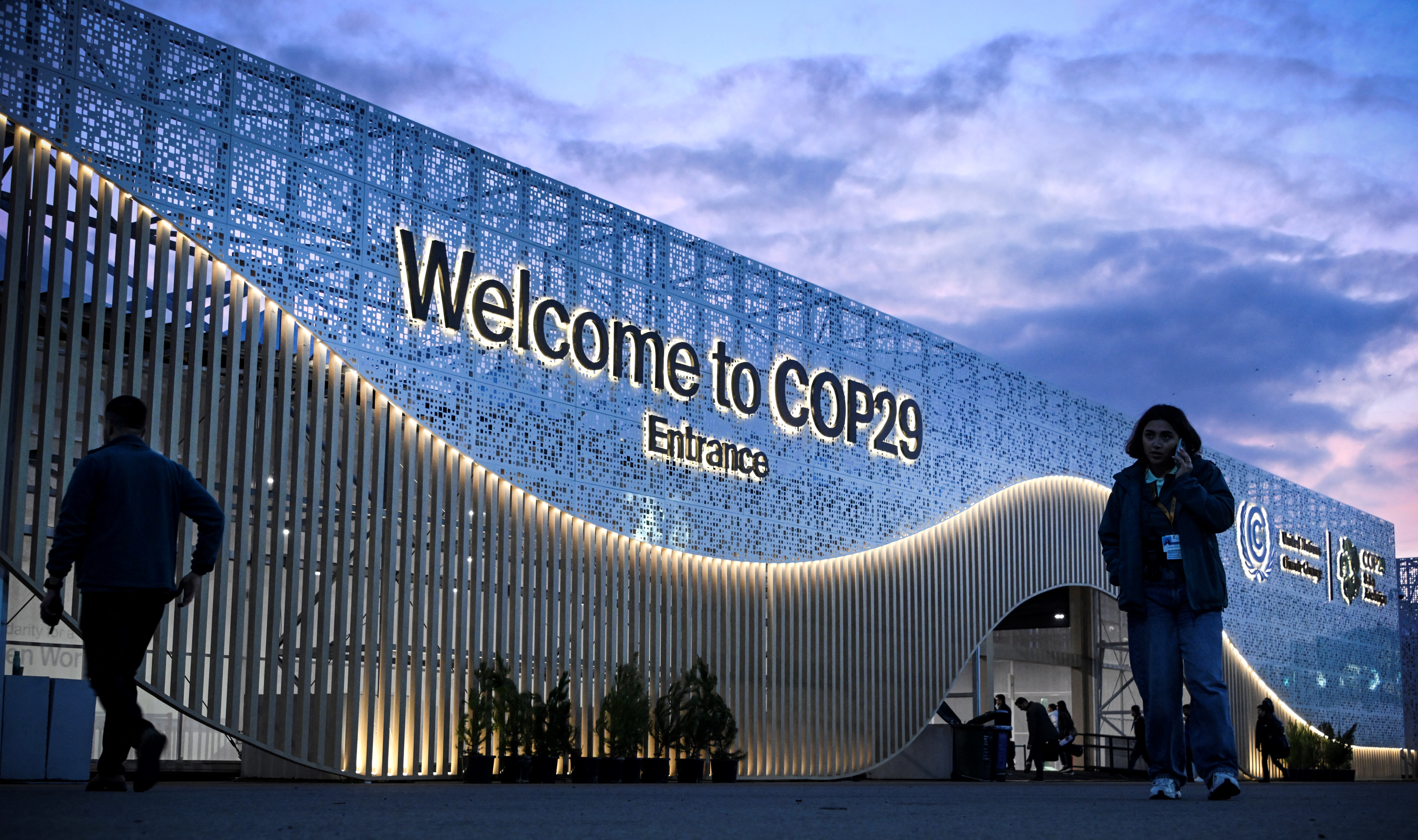 Pedestrians walk in front of the venue for the COP29 Summit in Baku on November 10, 2024, on the eve of the UN Climate Change Conference