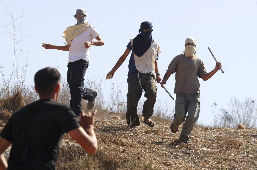 Masked Israeli settlers attack Palestinians in the West Bank village of Assira al-Kibliya. [File: Nasser Ishtayeh/AP]