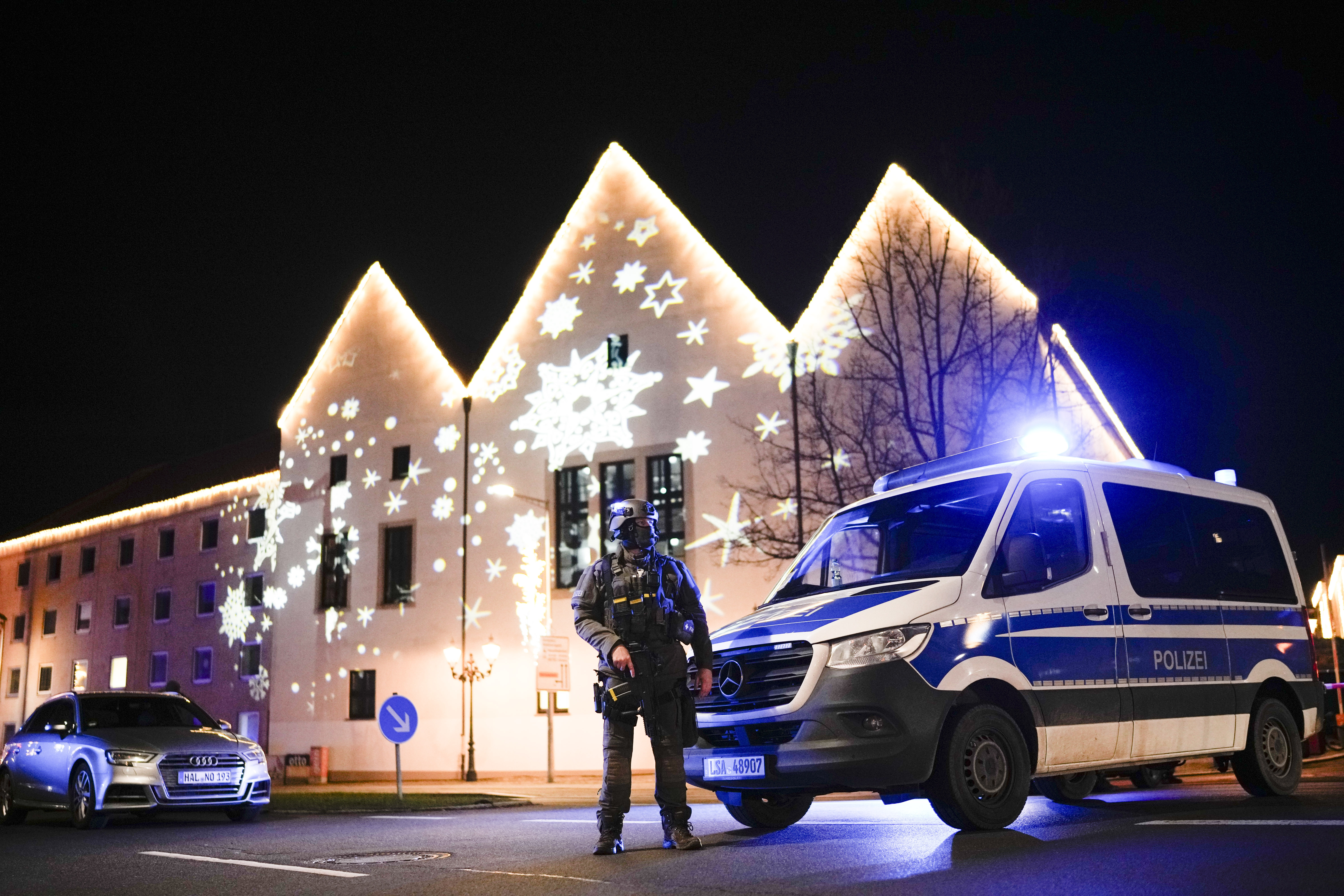 A police vehicle and officer near a Christmas market.