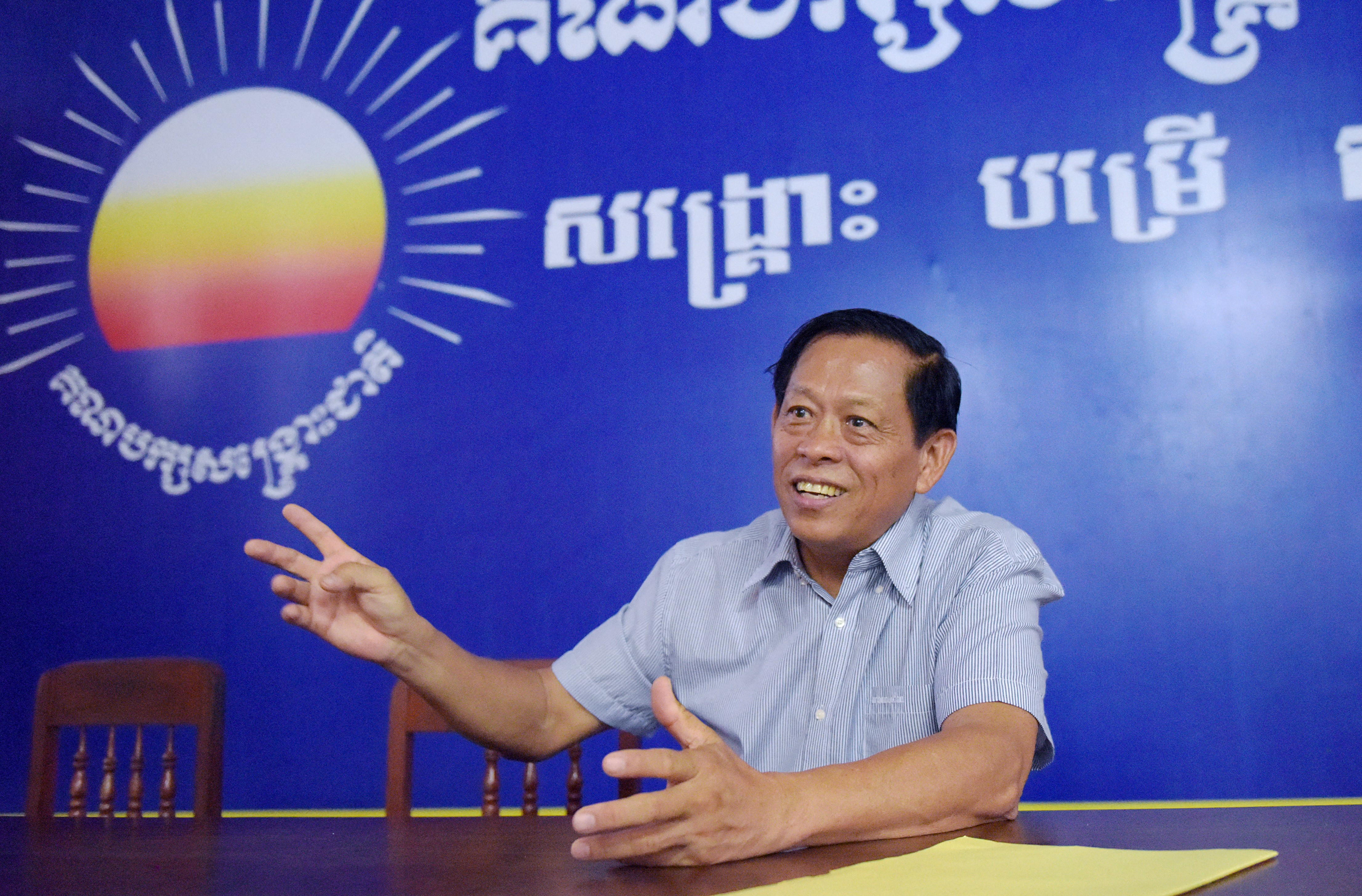 a man sits in front of a blue banner