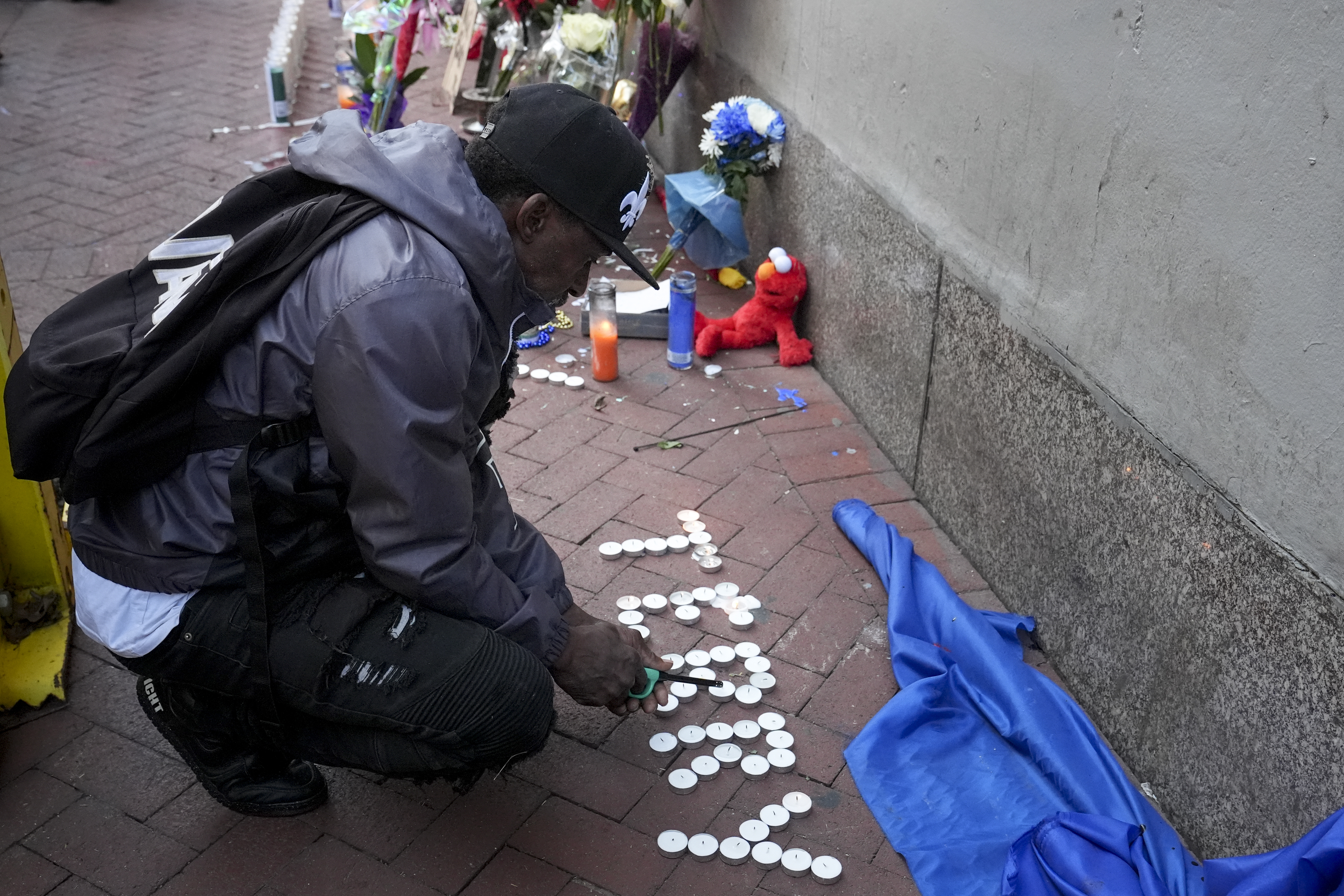 Eddie Williams lights candles for his uncle, who was killed in a deadly truck attack, at a memorial to the victims on Bourbon Street in the French Quarter, Friday, Jan. 3