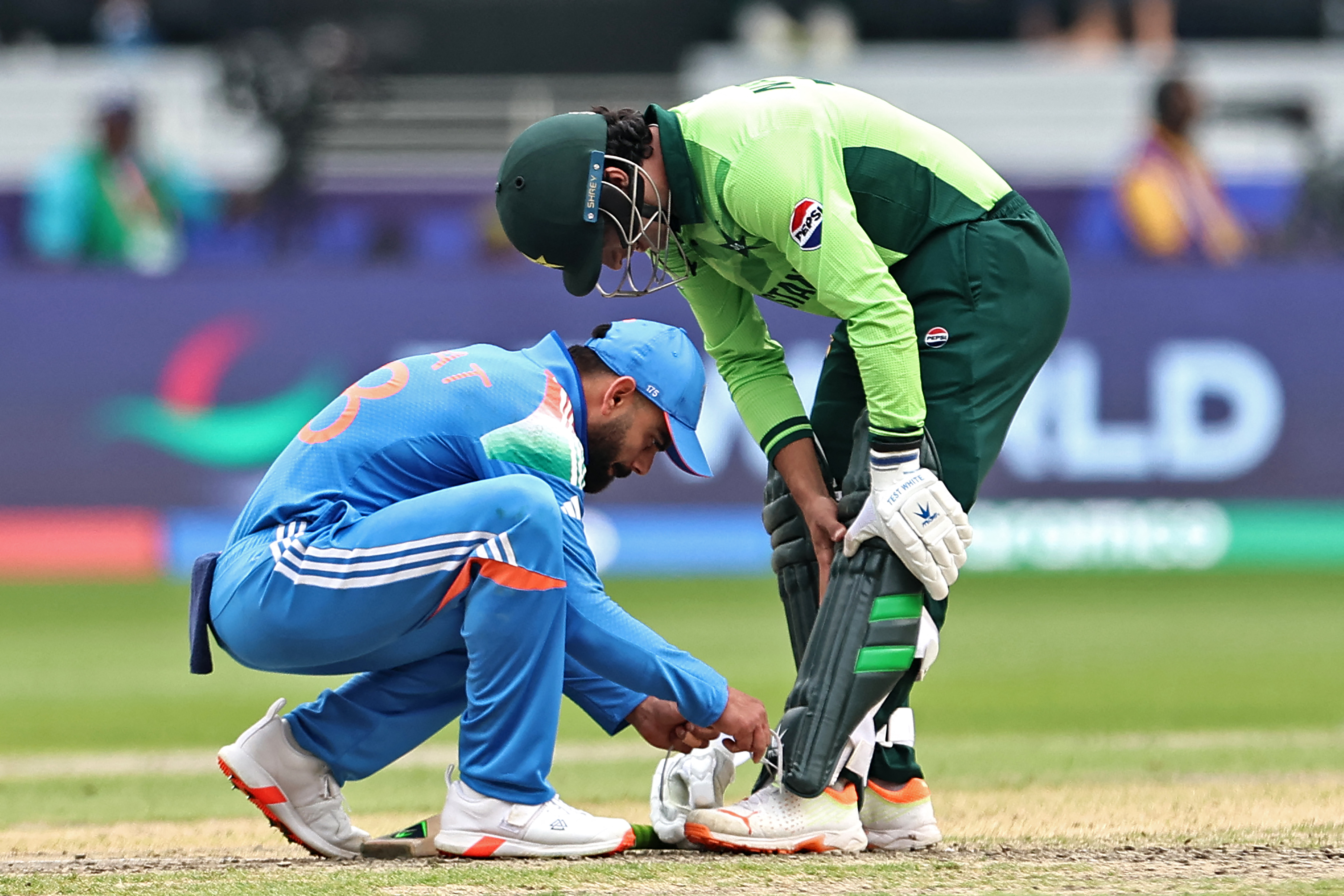 India's Virat Kohli (L) helps Pakistan's Naseem Shah in tying his shoelace during the ICC Champions Trophy one-day international (ODI) cricket match between Pakistan and India at the Dubai International Stadium in Dubai on February 23, 2025. (Photo by FADEL SENNA / AFP)